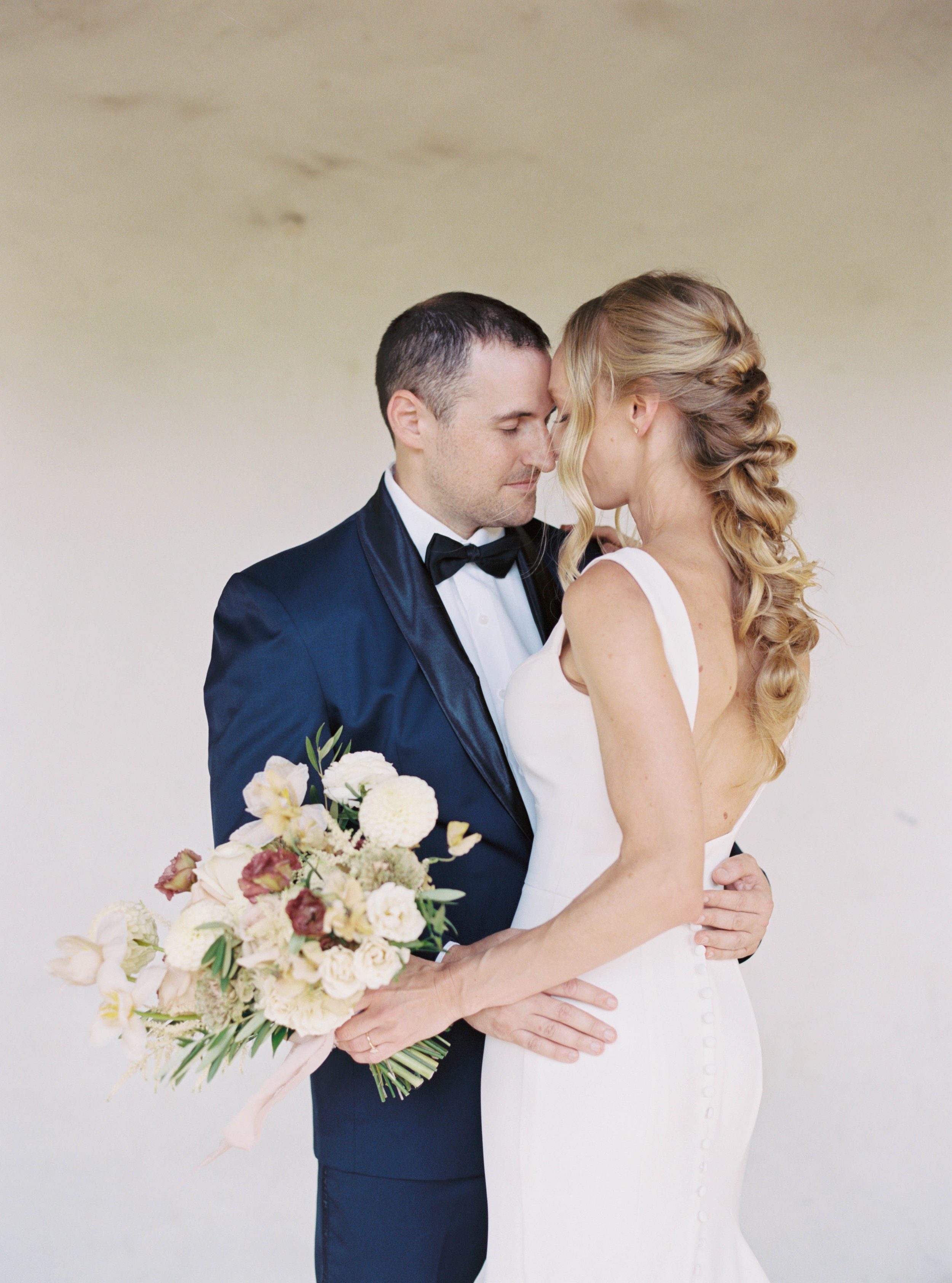 Bride with natural glam makeup and soft bridal hairstyle sharing a romantic moment with her partner on wedding day
