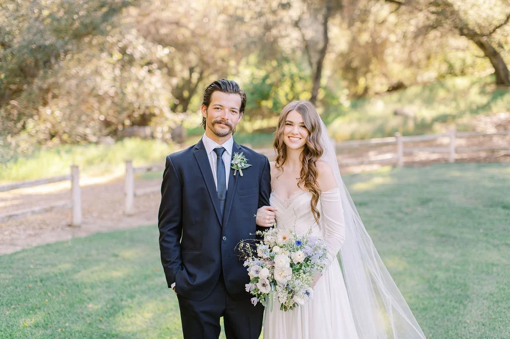 Bride with soft, radiant bridal glam standing confidently with her partner during outdoor wedding portraits