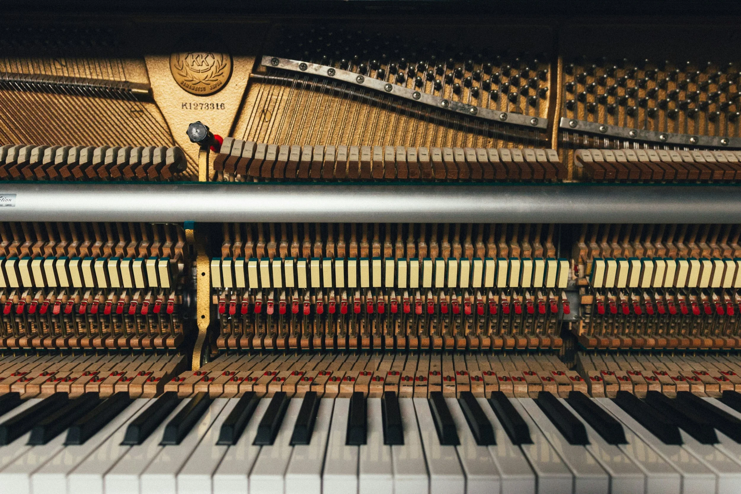 Close-up view of the interior strings, keys, and hammers of a piano.