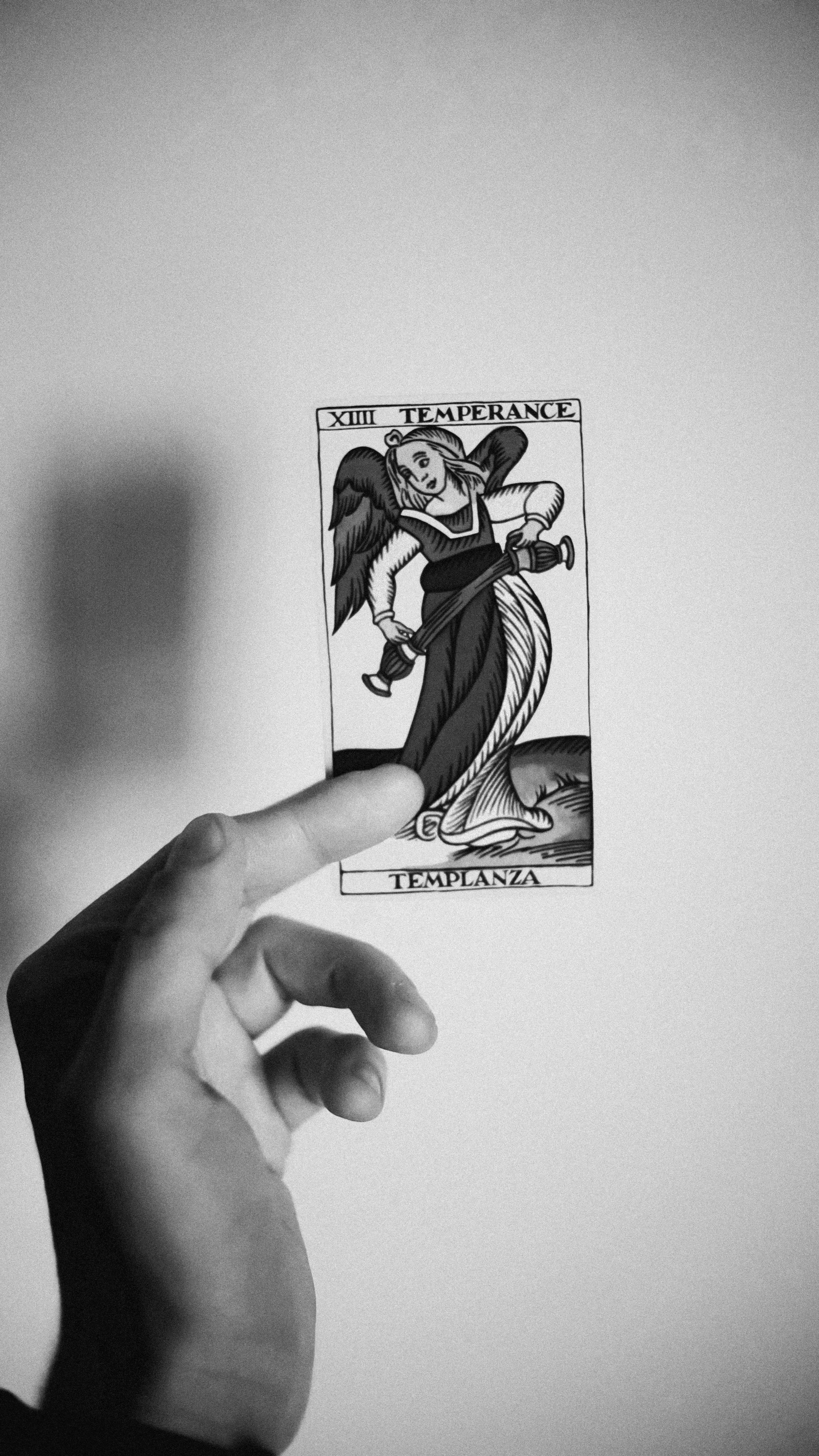 Black and white tarot card depicting a woman with wings, holding a sword, with a lion's face at her feet, labeled 'Temperance' and 'TEMPLANZA'.
