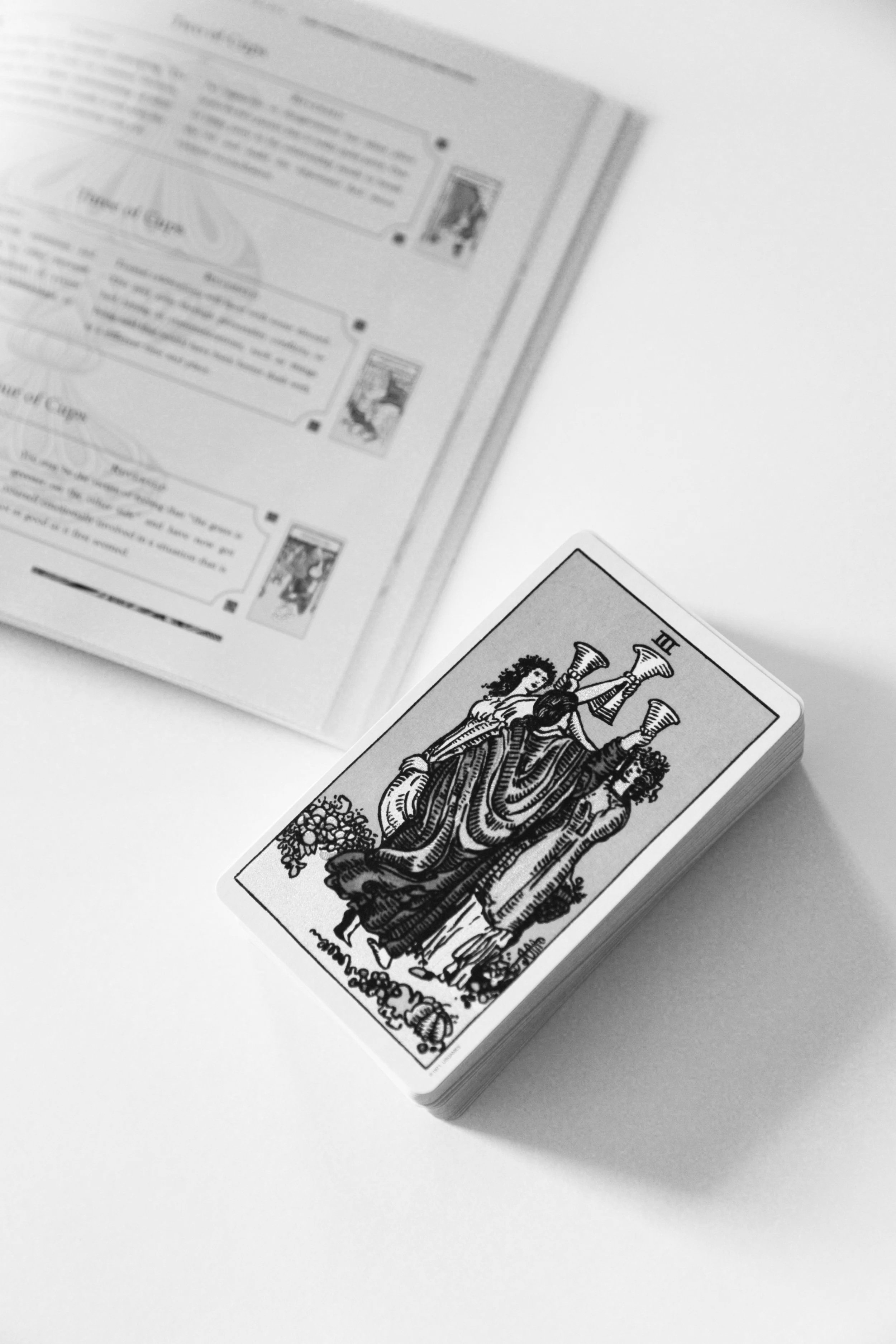A tarot card deck with the Justice card face up on a white surface, with an open instruction booklet in the background.