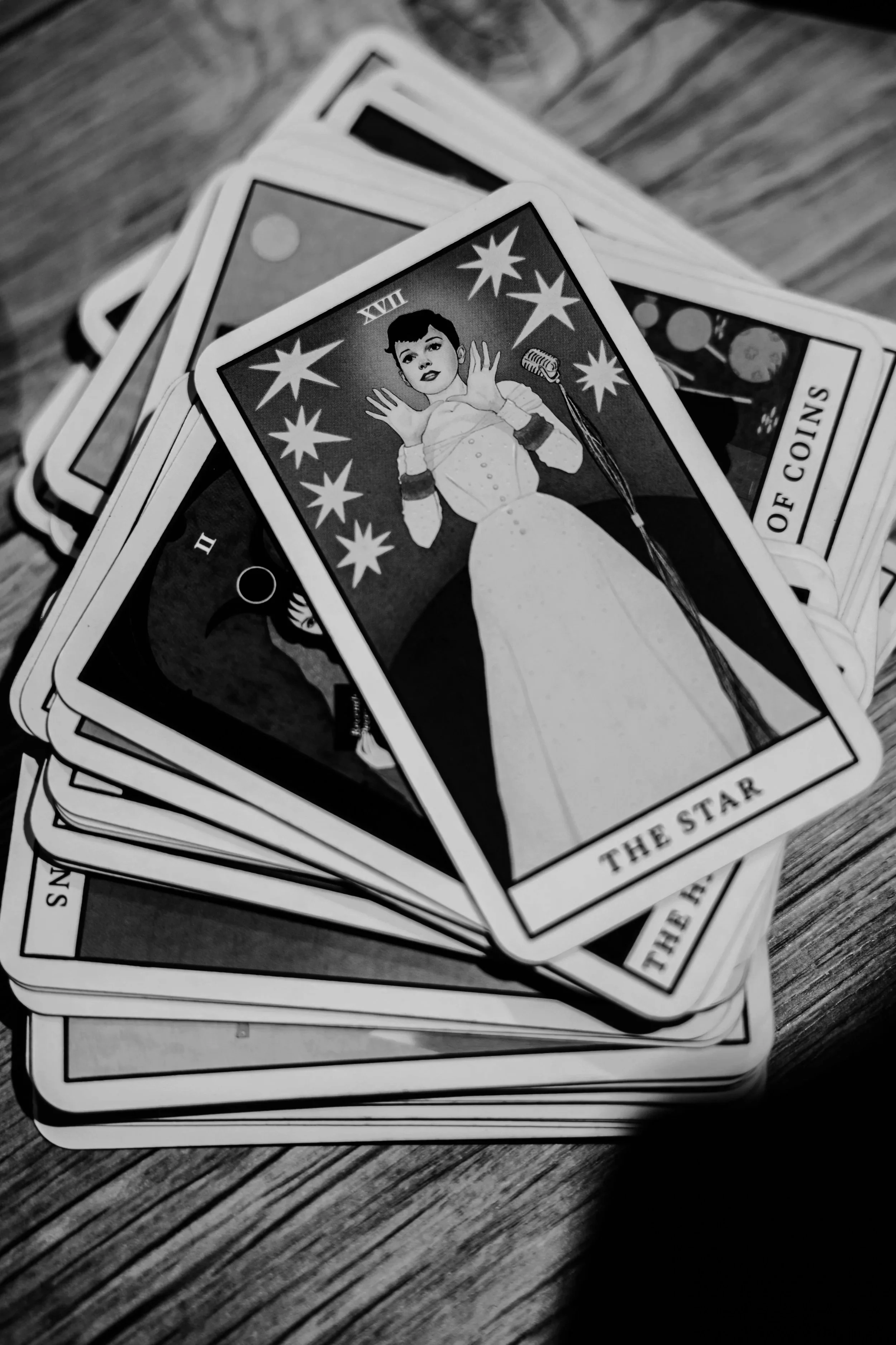 A spread of Tarot cards featuring the card "The Star" with an illustration of a woman with short hair wearing a long dress. The image is black and white.