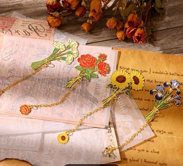 Metal flower bouquets and bookmarks on paper and a wooden surface.