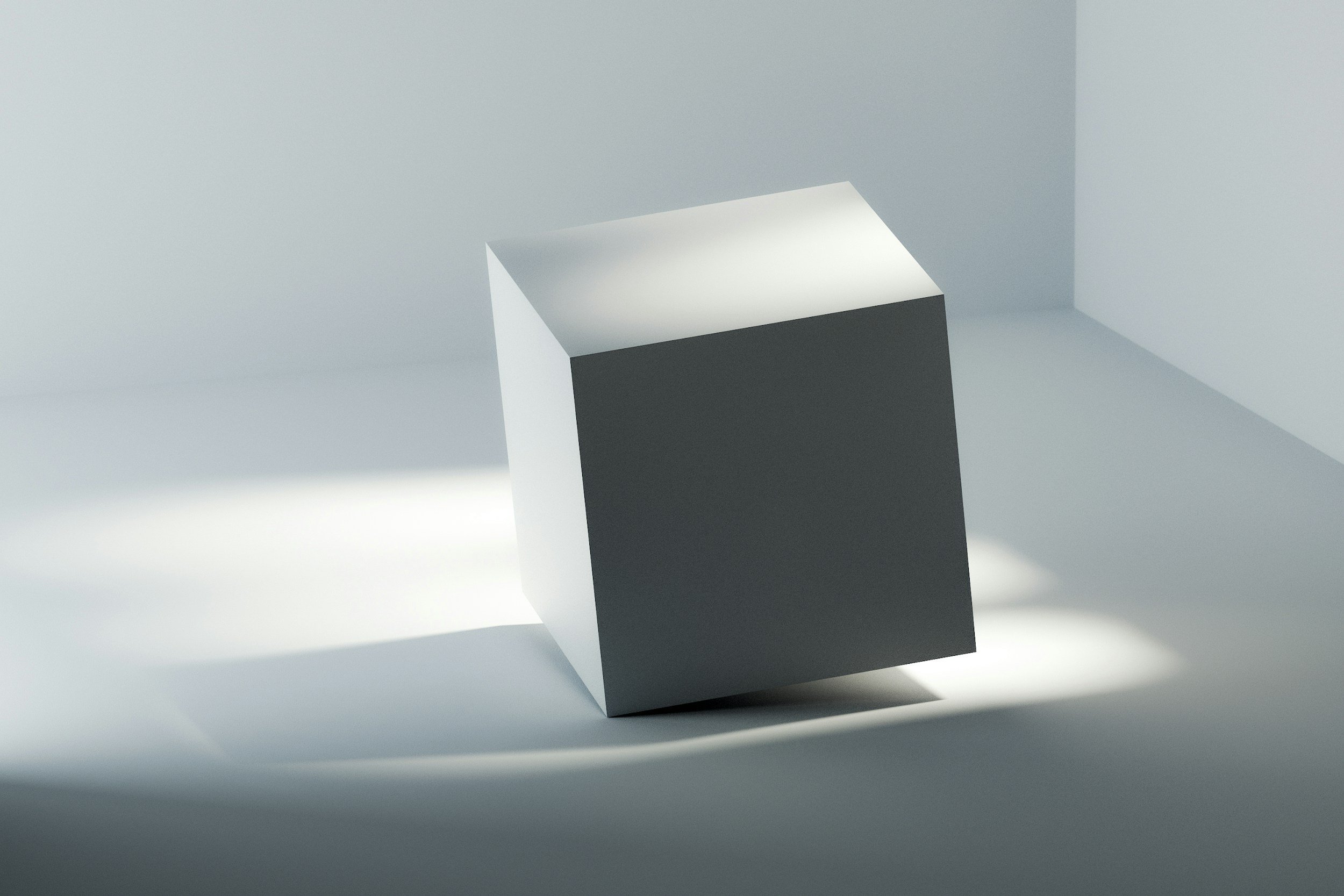 A gray cube with a light source creating shadows on a white surface and background.