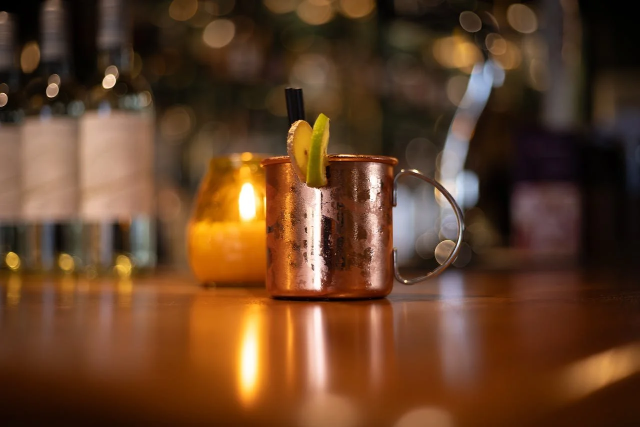 Moscow mule on the bar with a lit candle visible in the blurred background.