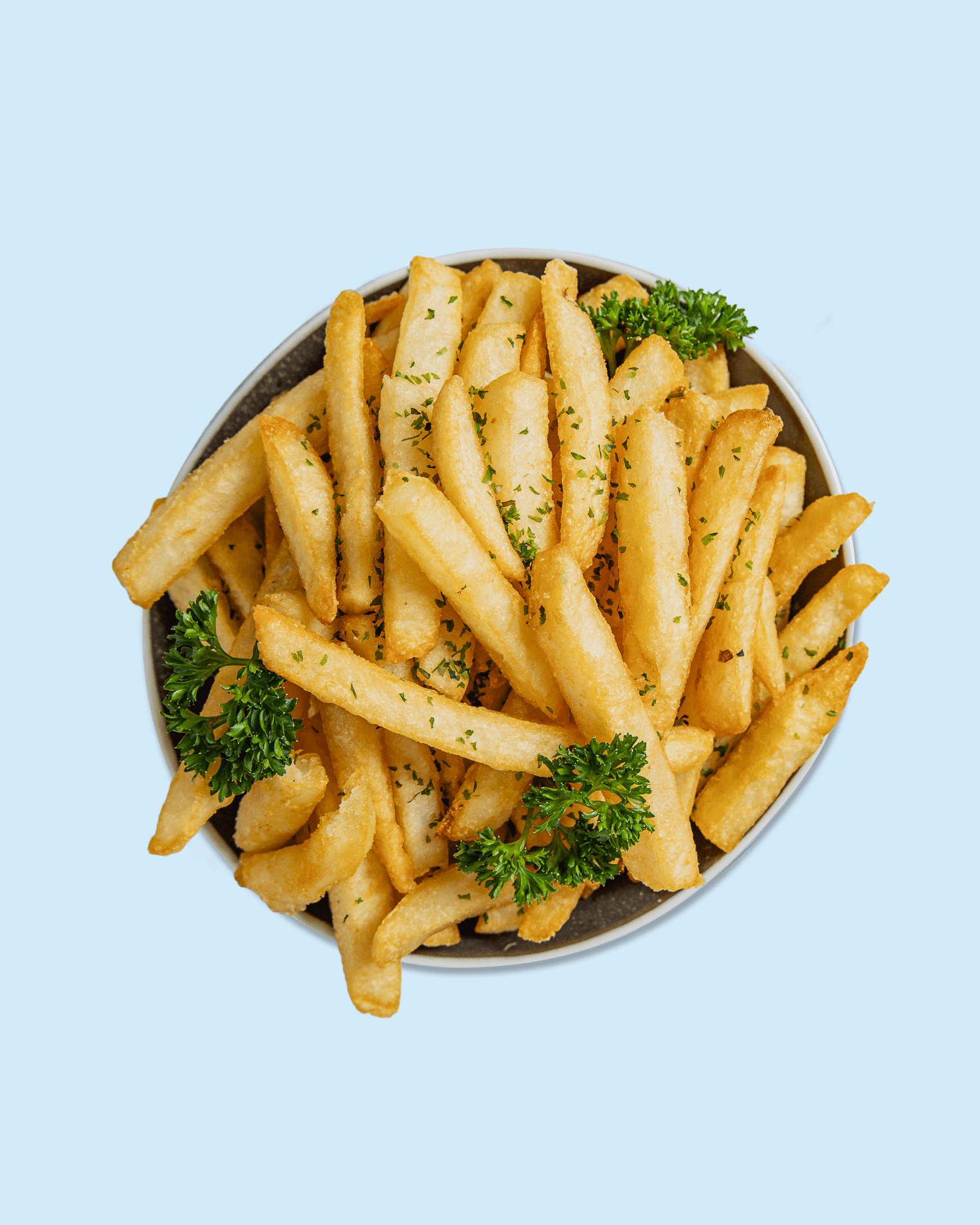 A bowl of French fries garnished with parsley.