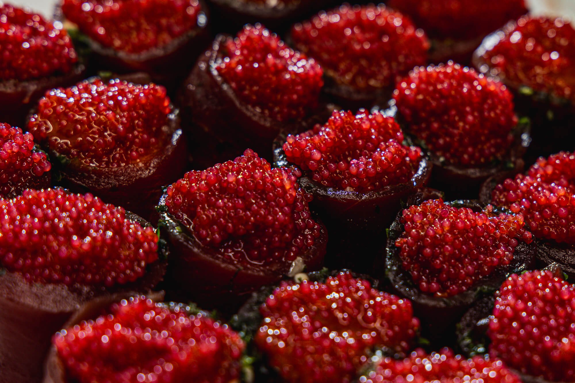Close-up of sliced fresh strawberries with vibrant red color, showing seed-filled surface and dark green leaves.