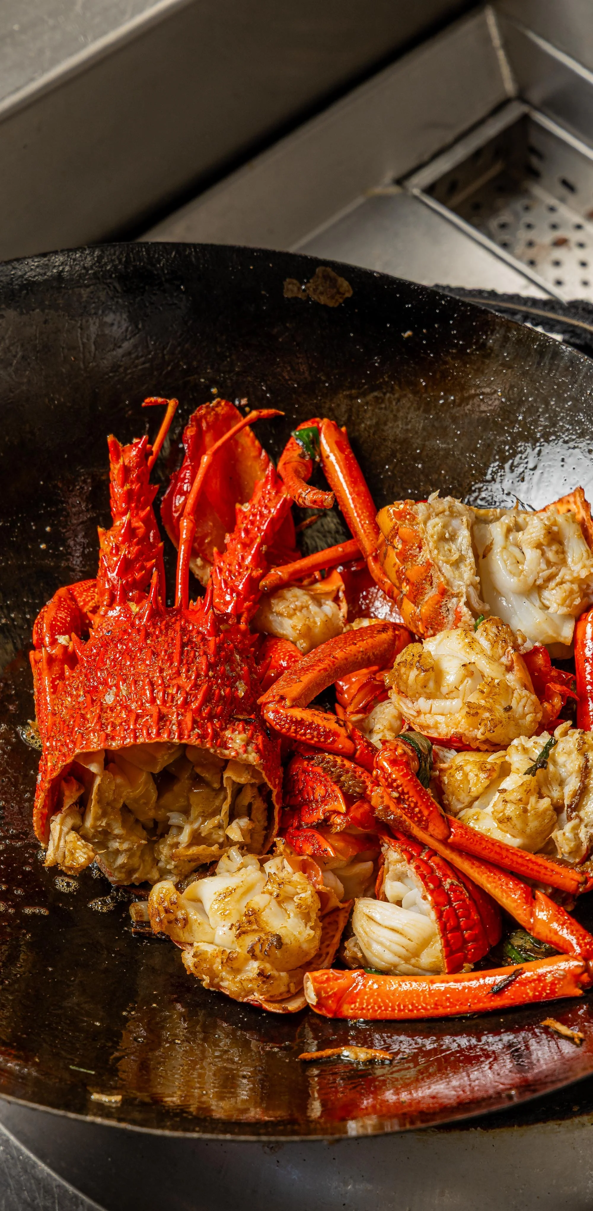 Lobster and lobster meat being cooked in a black skillet.
