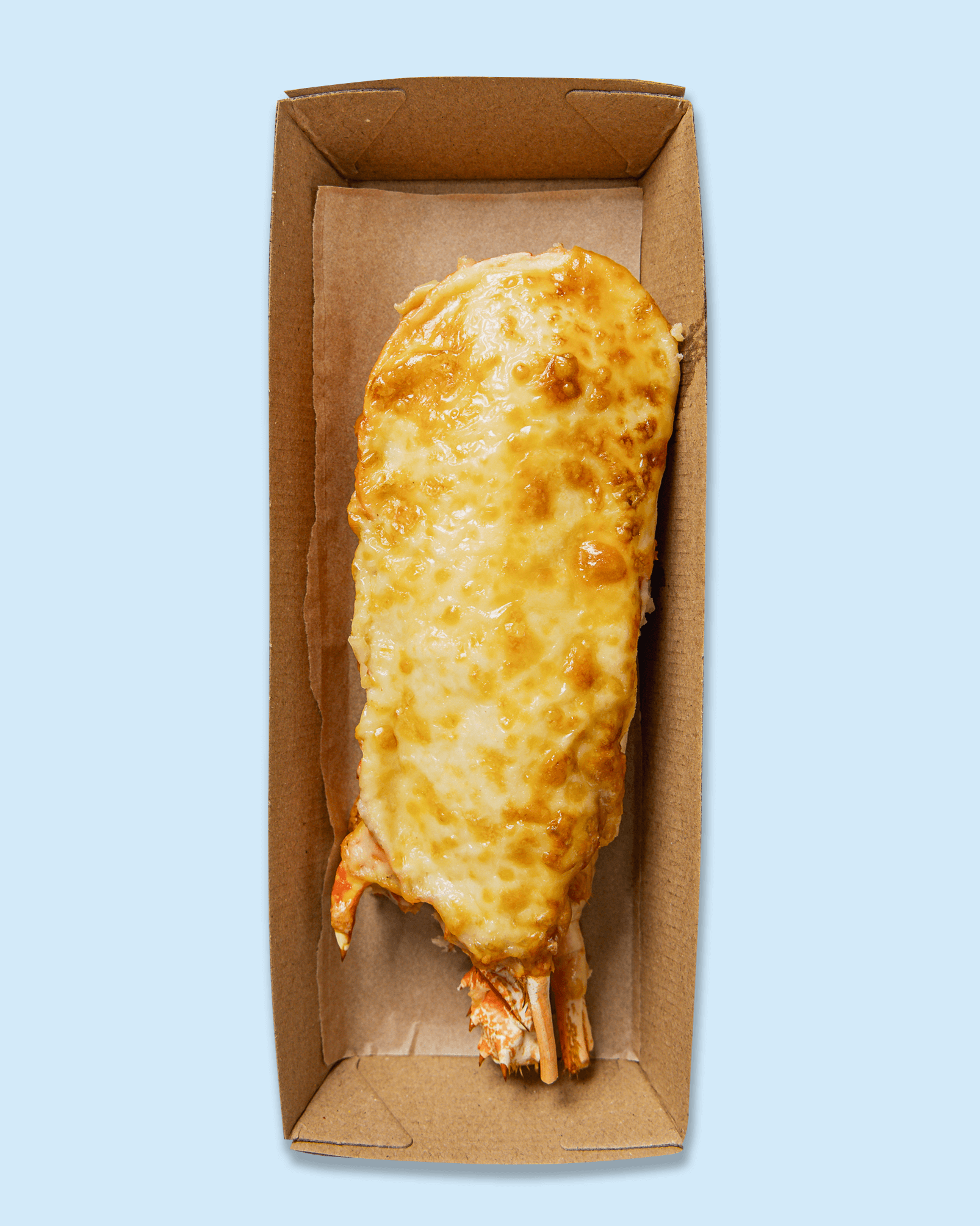 Lobster tail topped with melted cheese, inside a cardboard takeout container.