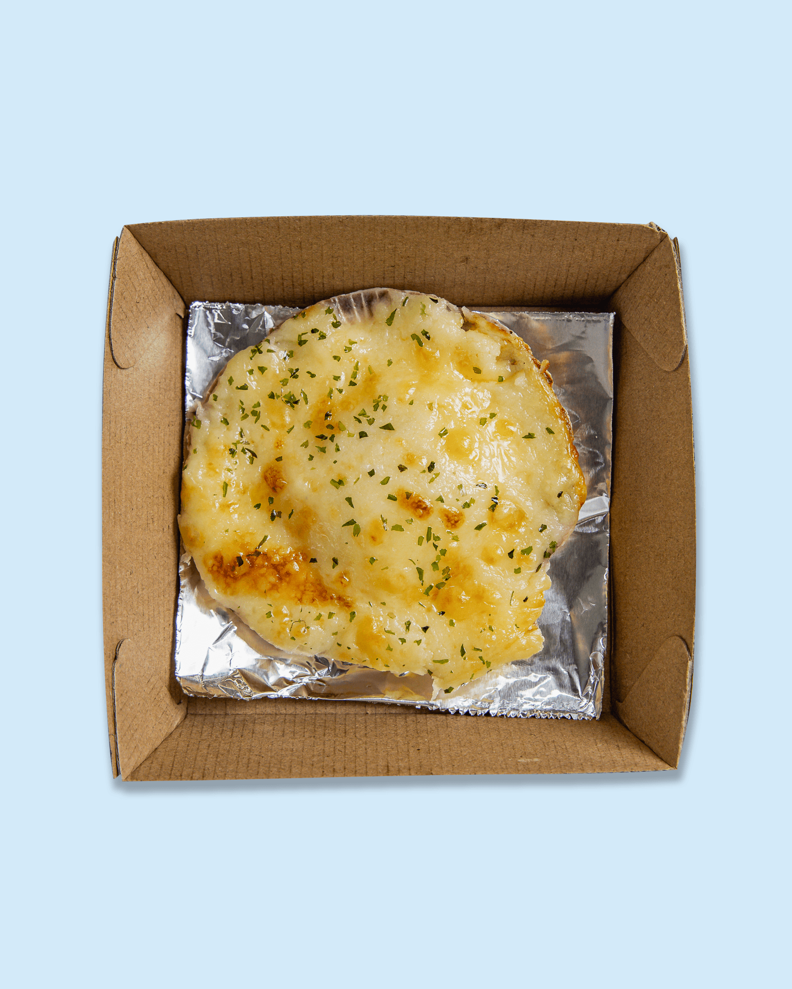 Cheeseless pizza with melted cheese and herbs in a cardboard takeout box and foil lining.