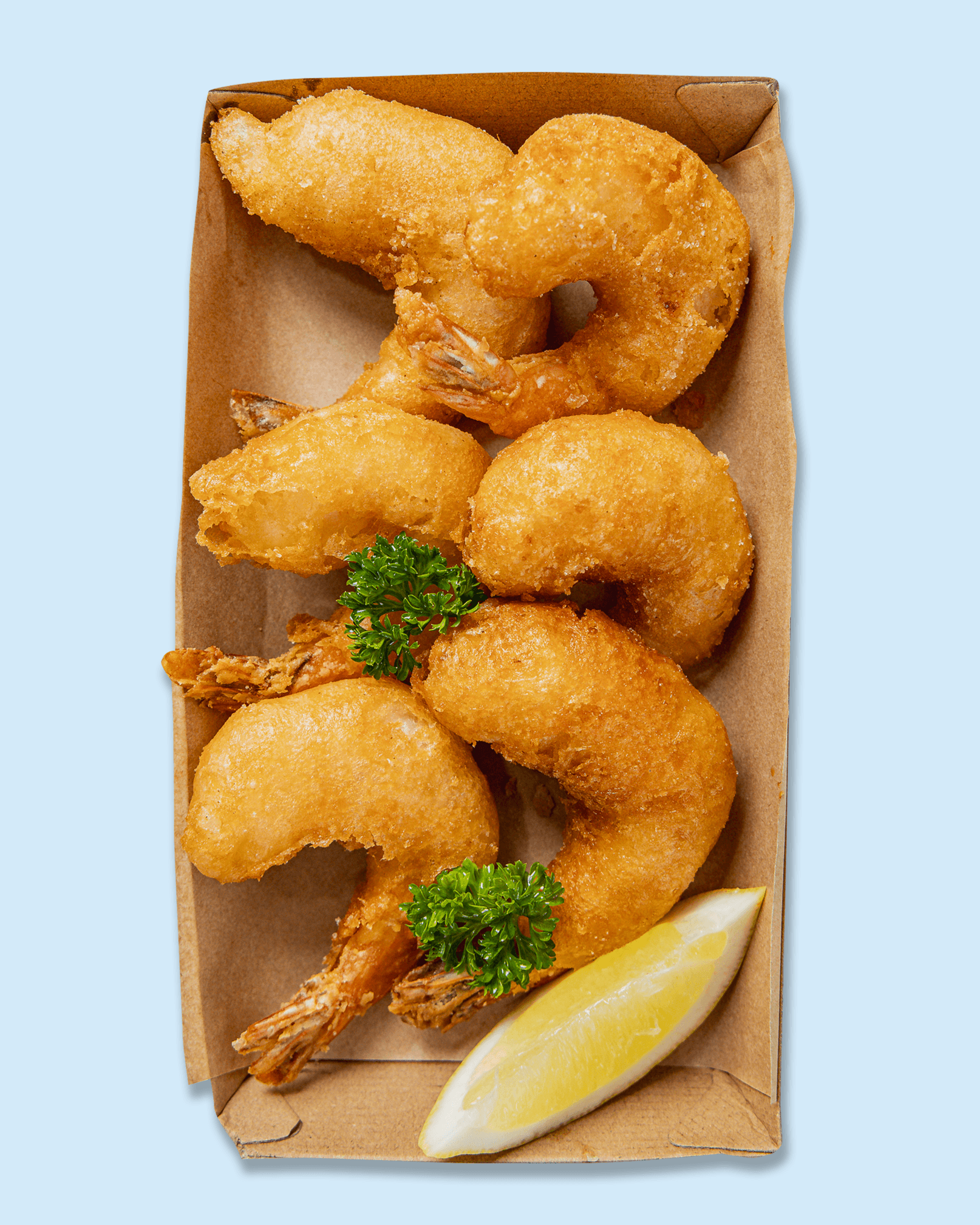 Fried shrimp and battered fish in a cardboard tray, garnished with parsley and a lemon wedge, on branded paper for NICHOLAS catering and events.