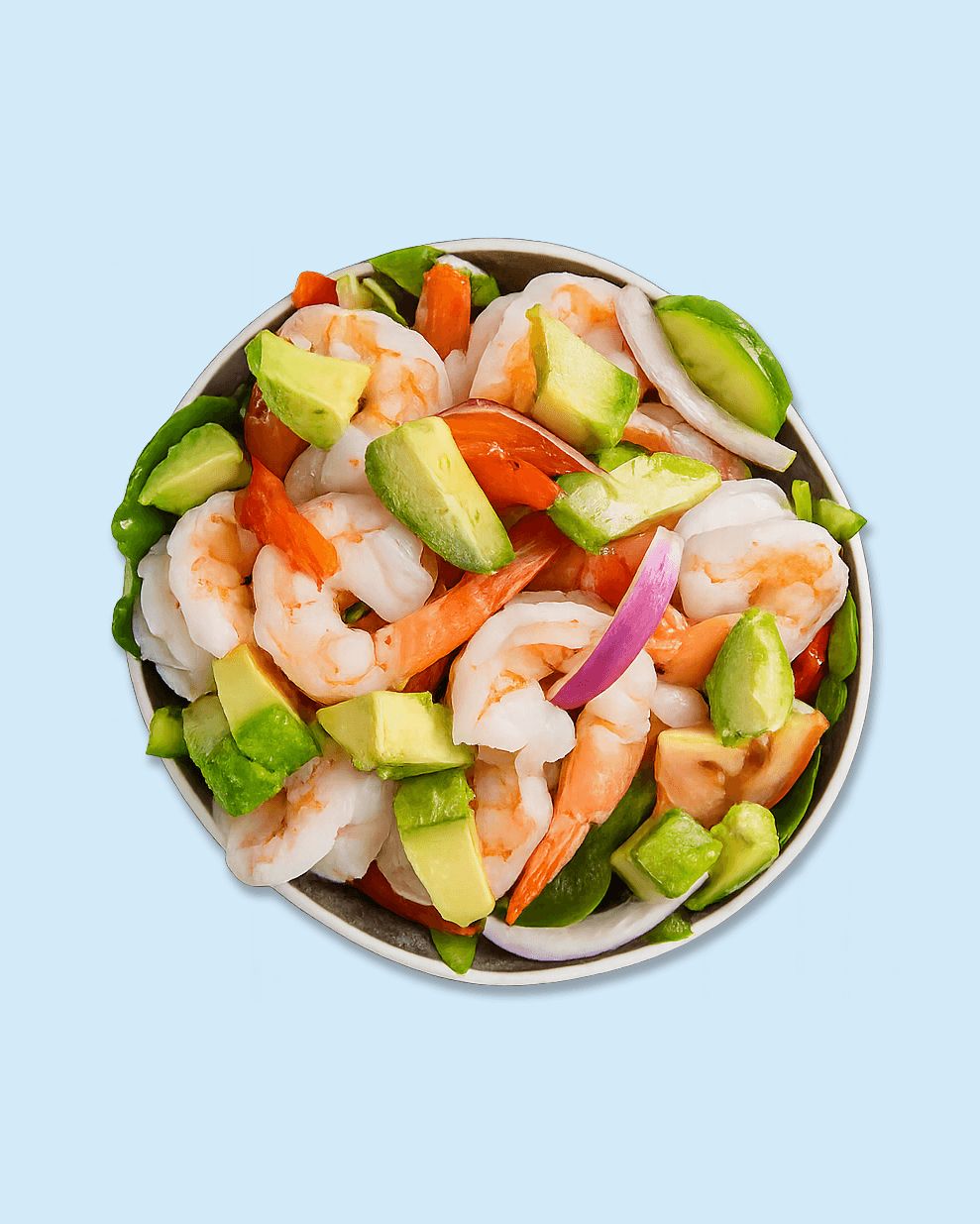 Close-up of a seafood salad with shrimps, avocado, sliced onions, and tomatoes in a bowl on branded paper.