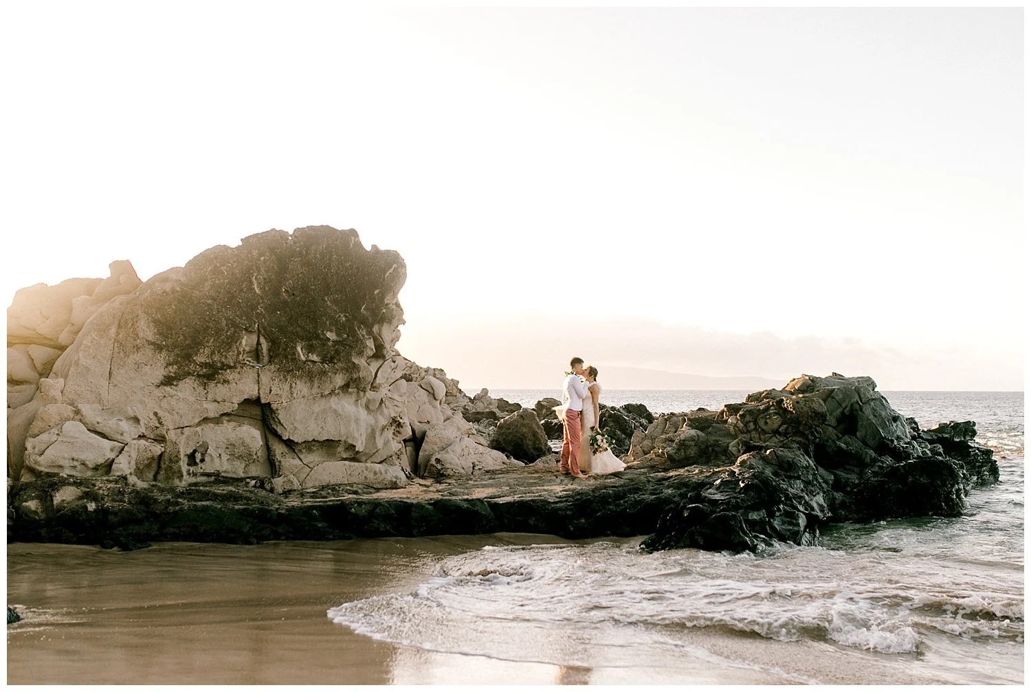 Bride and groom on lava rocks on Maui beach