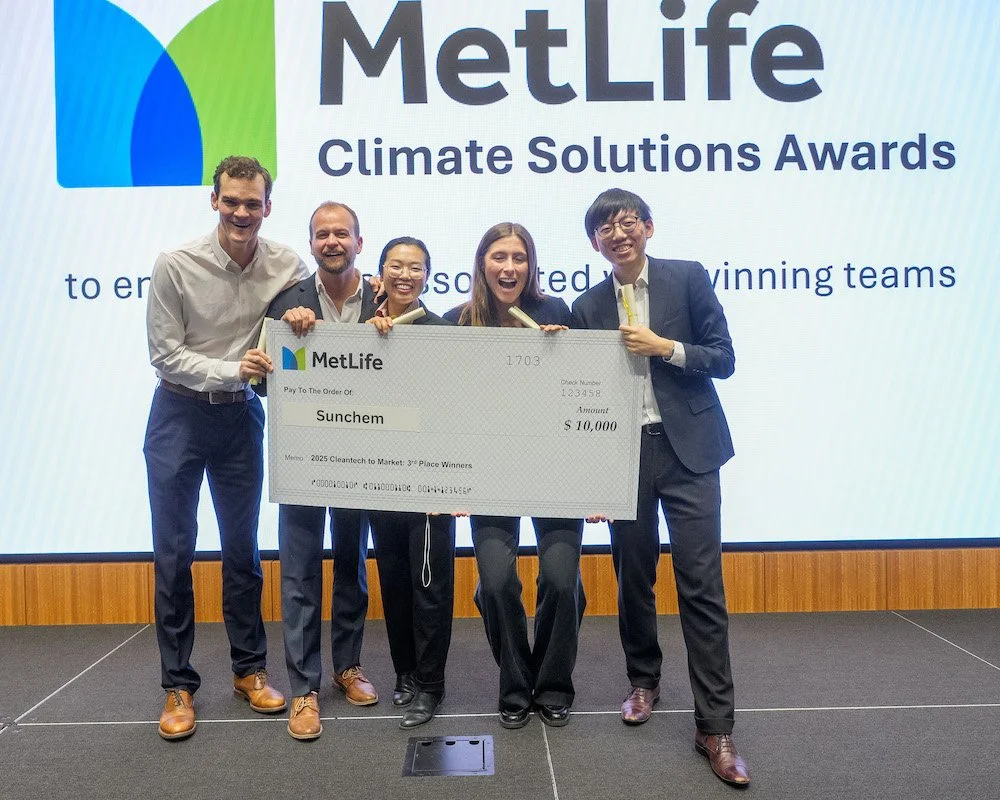 Group of five people standing on stage holding a large check at the MetLife Climate Solutions Awards event.