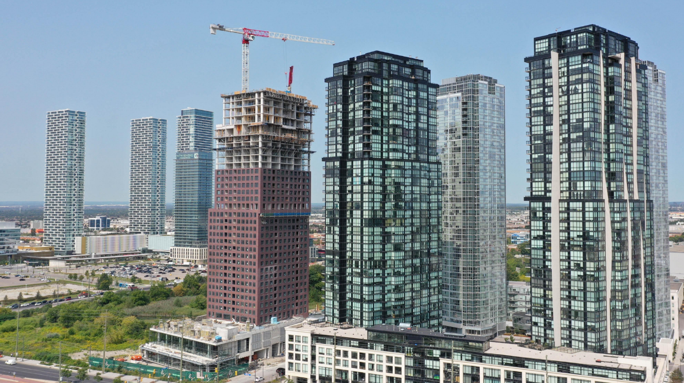 High-rise buildings and skyscrapers in an urban cityscape, with one under construction featuring a crane at the top.