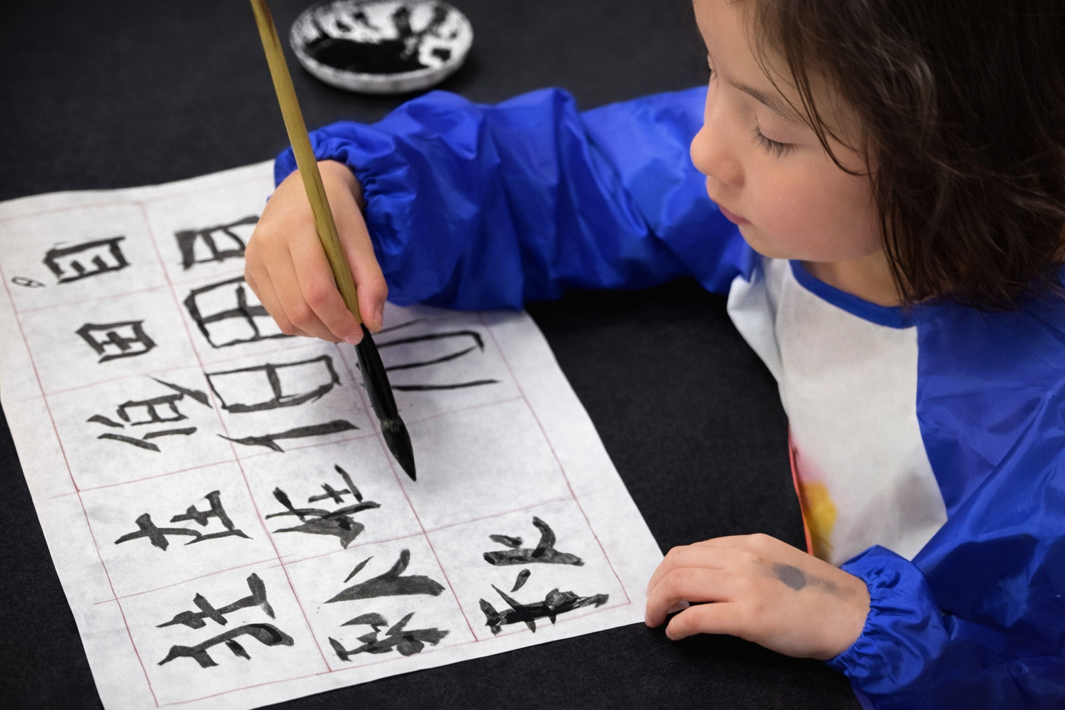 elementary school child writing chinese calligraphy during an after school class at trust montessori school