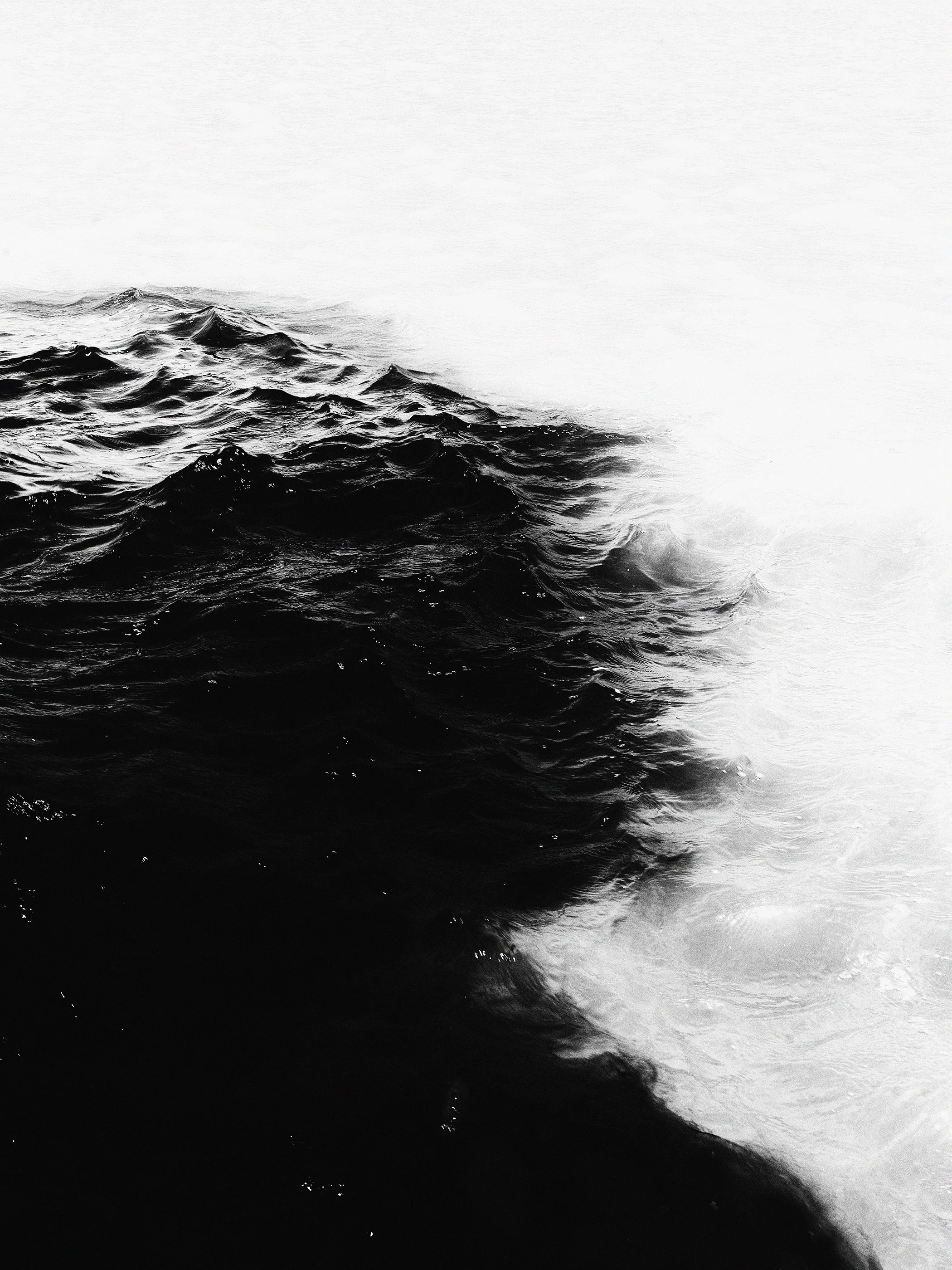 Mar de ondas negras com espuma branca nas pontas, vista em preto e branco.