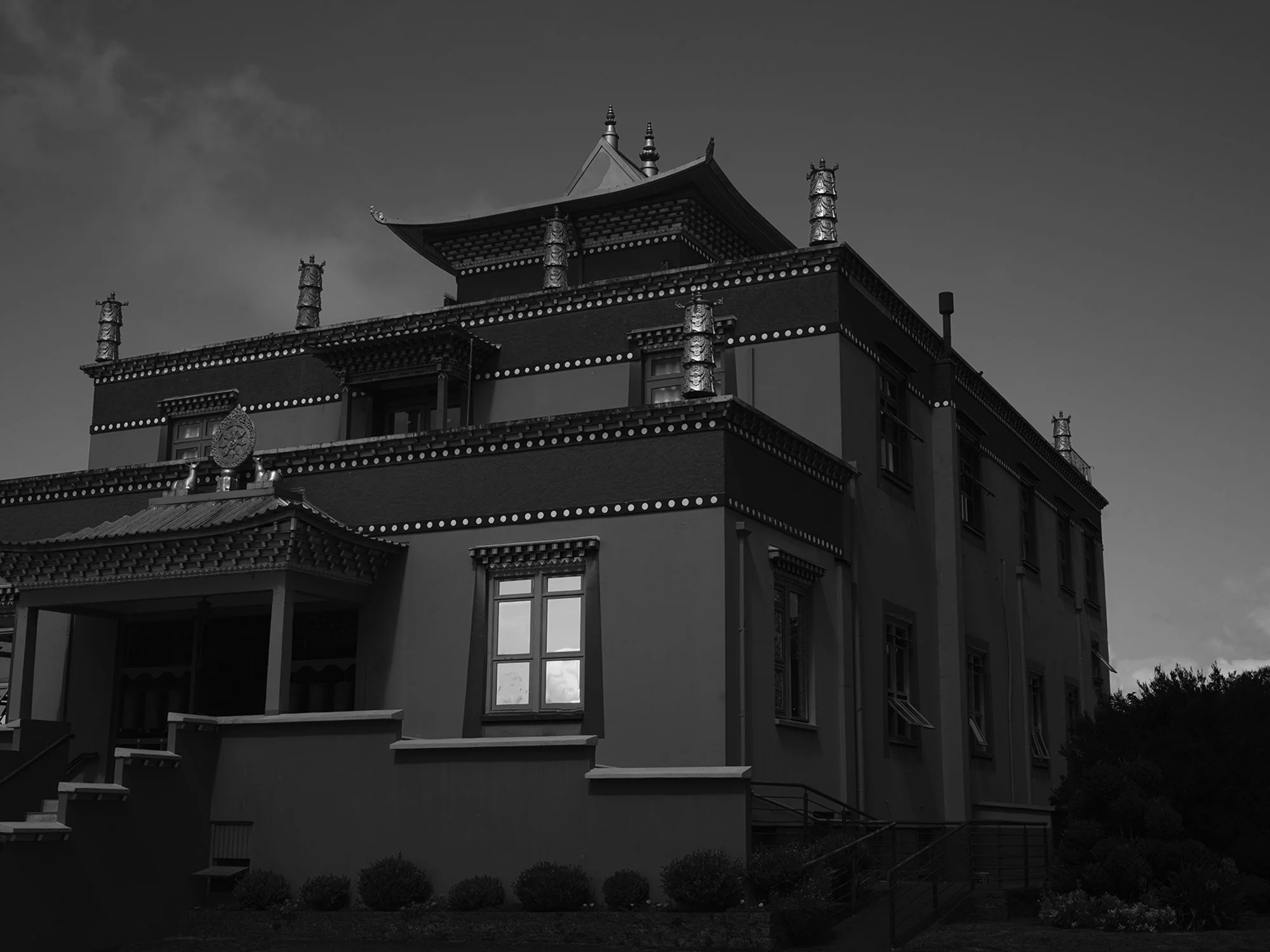 Edifício com arquitetura tradicional asiática, com telhados curvos e detalhes ornamentais, sob céu nublado.