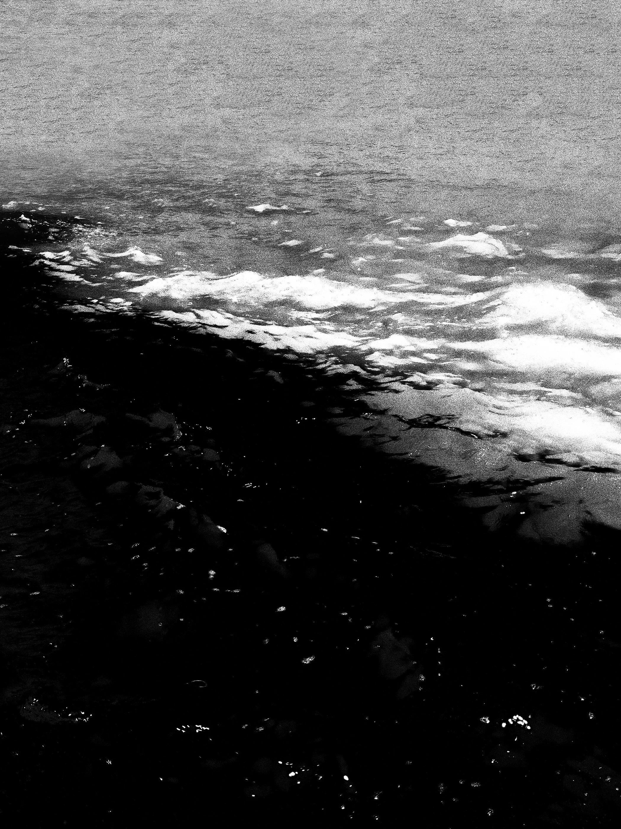 Imagem em preto e branco de ondas na superfície do mar.