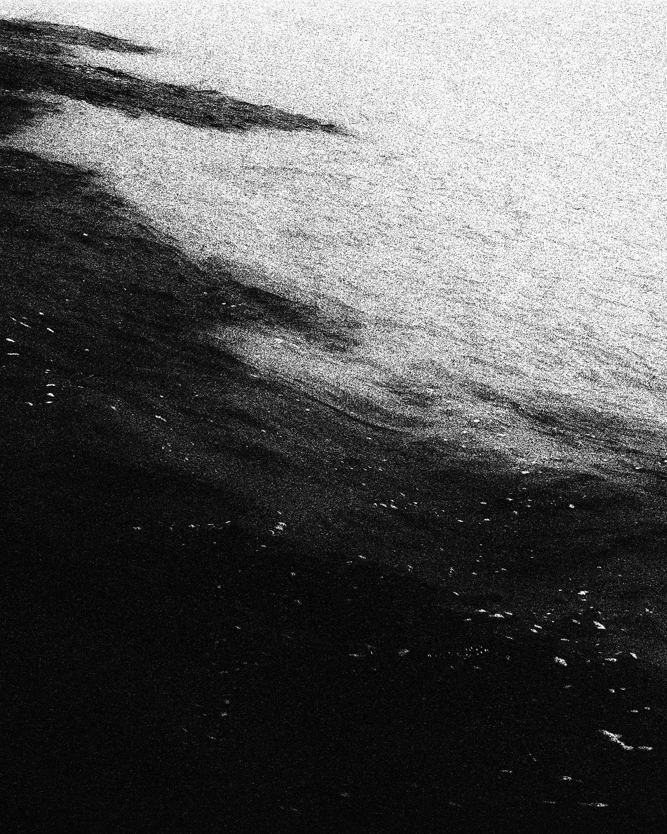 Foto em preto e branco de uma superfície de água, possivelmente um mar ou rio, com ondas suaves.