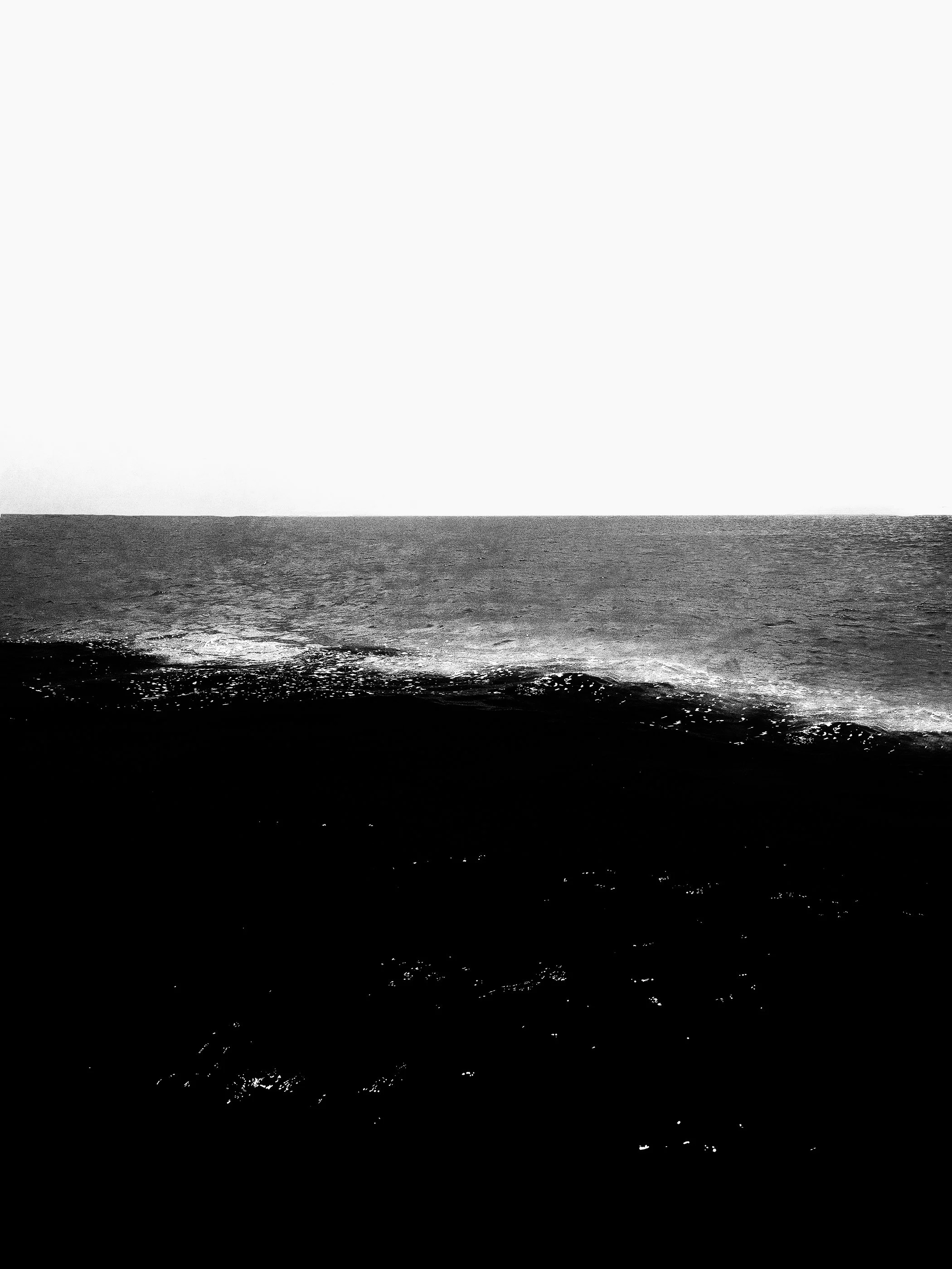 Paisagem de mar com ondas e céu vazio em preto e branco.