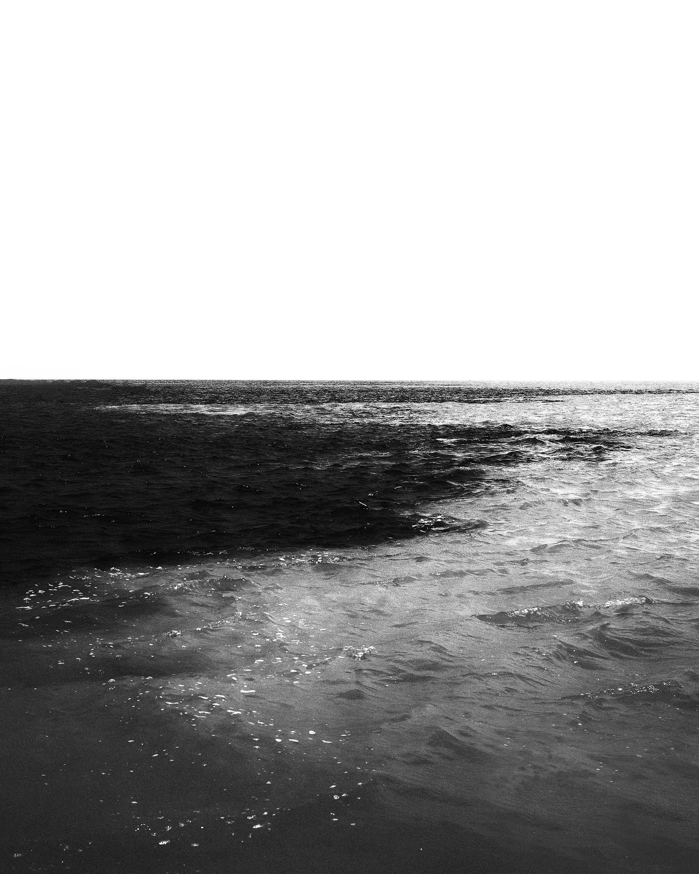 Mar aberto com ondas e céu nublado, em preto e branco.