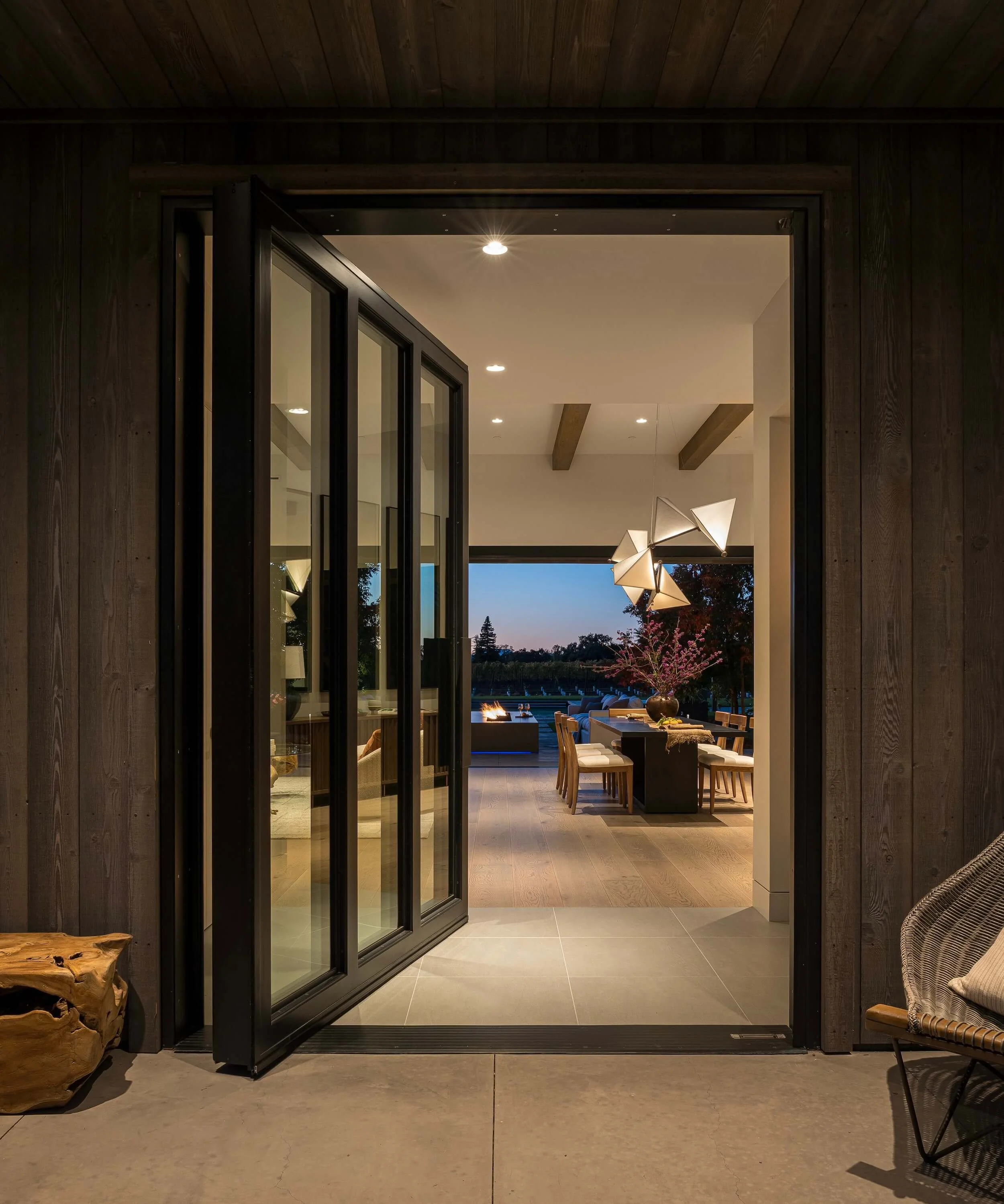 Seamless indoor-outdoor electrical integration for massive glass pivot doors, bridging hardwood interiors with stone courtyards in a Napa Valley residence.