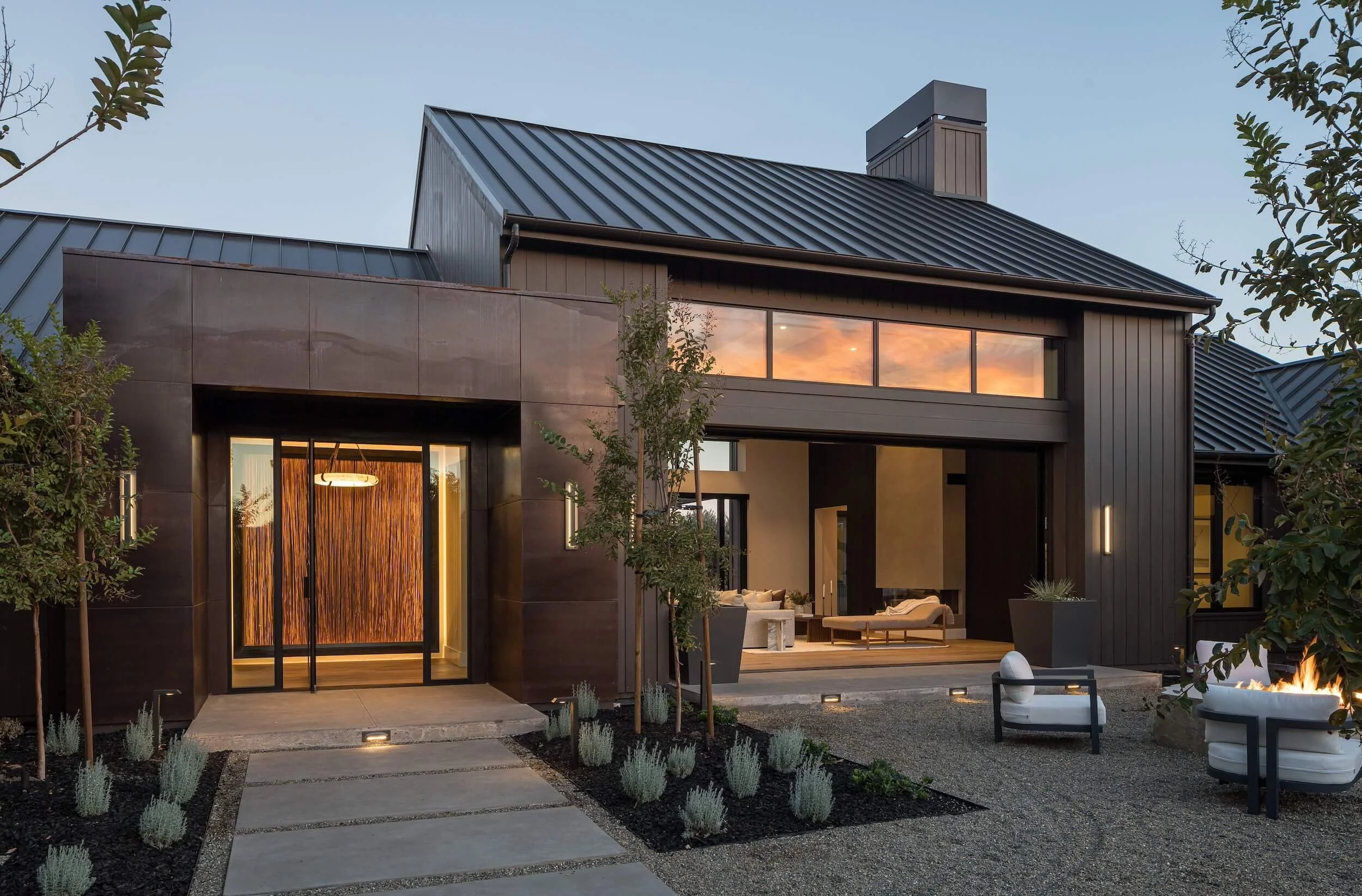 Modern front entryway at dusk featuring integrated stair lighting, landscape uplighting, and warm interior glow in St. Helena.