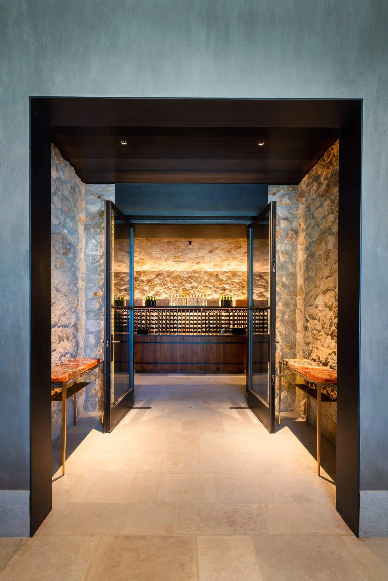 Transition view into the winery tasting room, highlighting the professional electrical contracting for large-scale pivot doors and automated lighting scenes.
