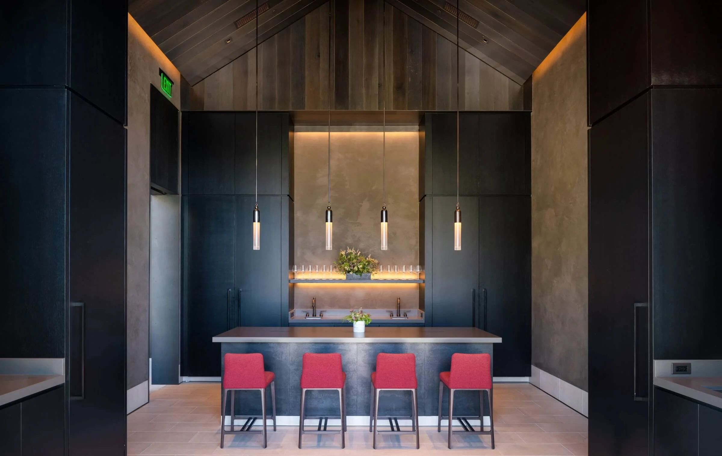 A luxury Napa winery tasting bar with integrated LED backlighting for a modern display and warm, directional pendant lights for the main service area