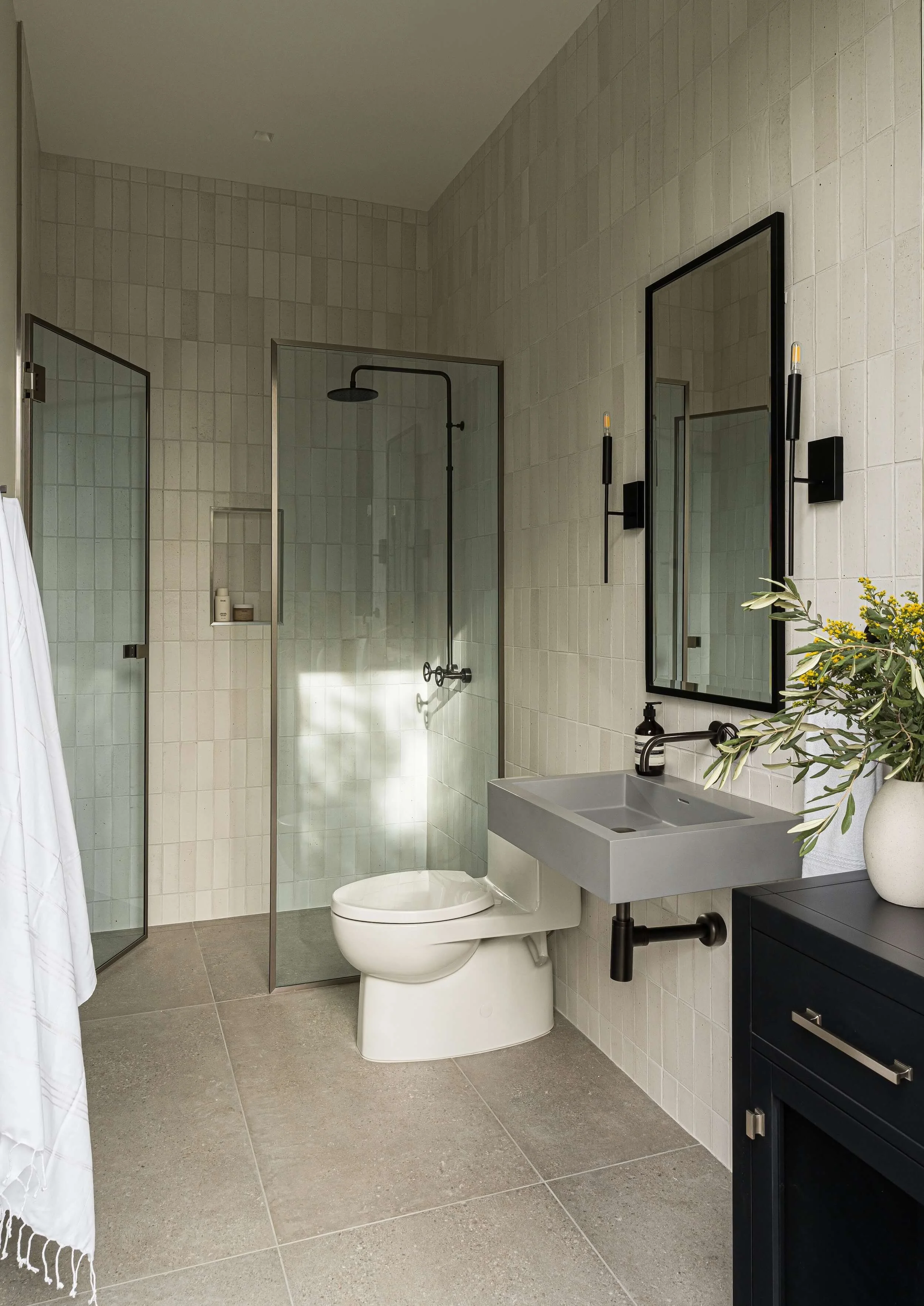Luxury modern bathroom featuring sleek black frame mirror with integrated lighting and minimalist sink vanity design.