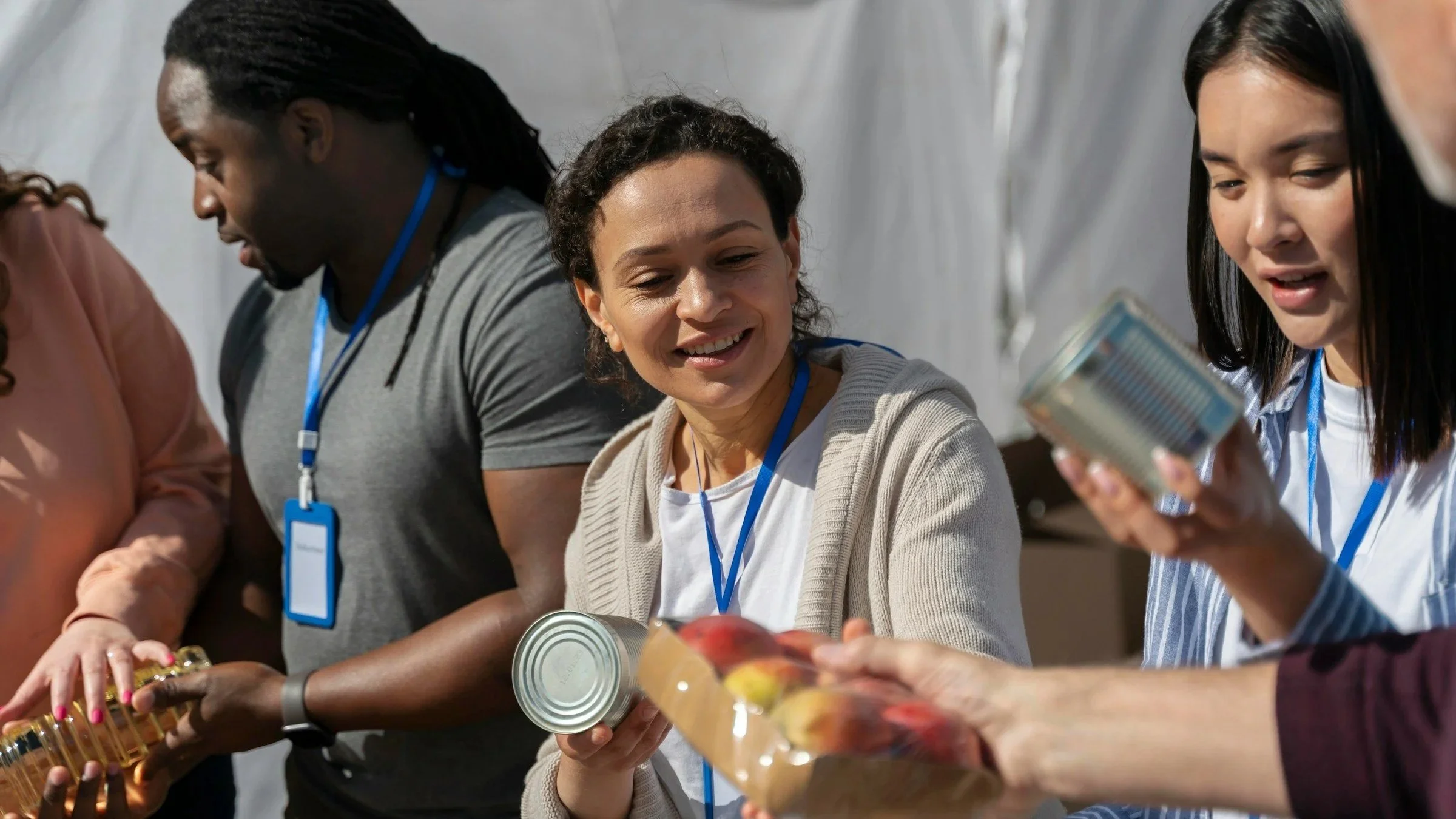 Group of diverse people handing out canned food and groceries at a community event.