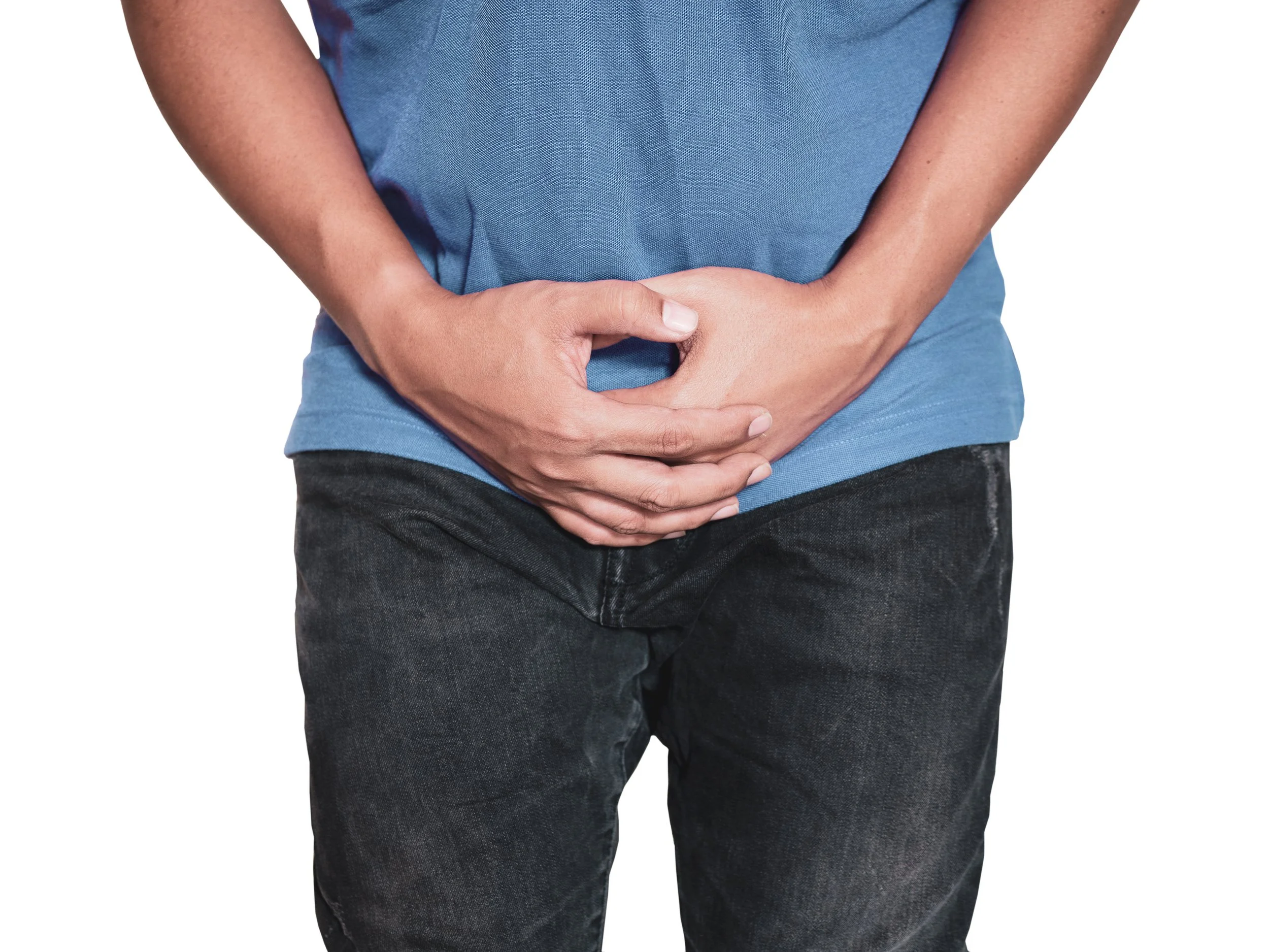 A person with tan skin and a slim build holding their stomach with both hands, wearing a blue shirt and dark jeans.