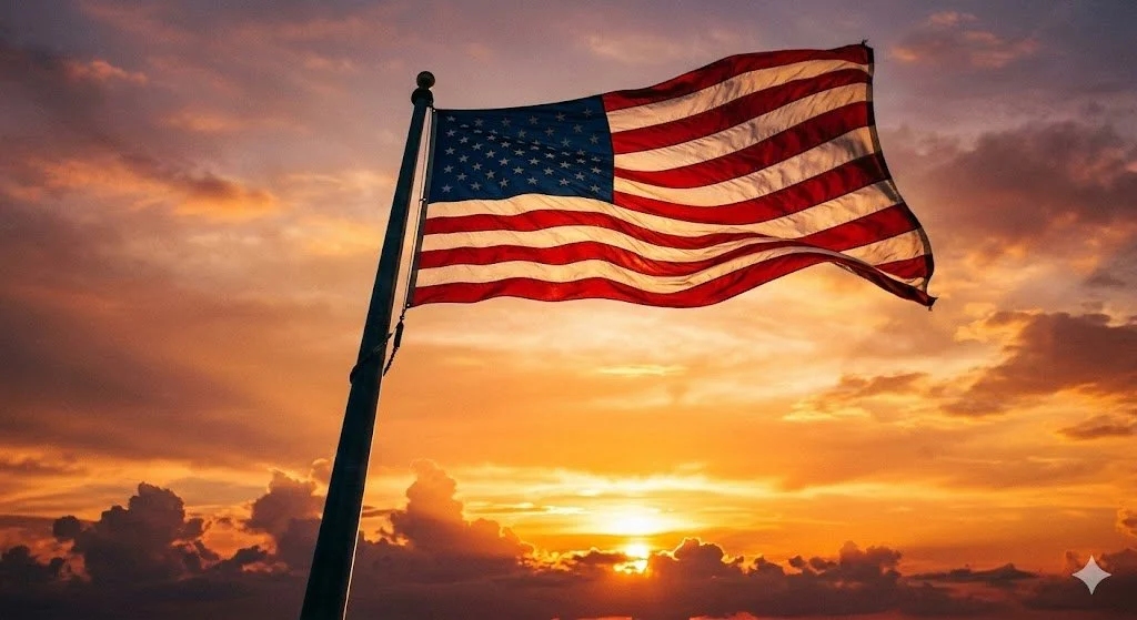 American flag waving in the wind at sunset with orange and purple sky and clouds.