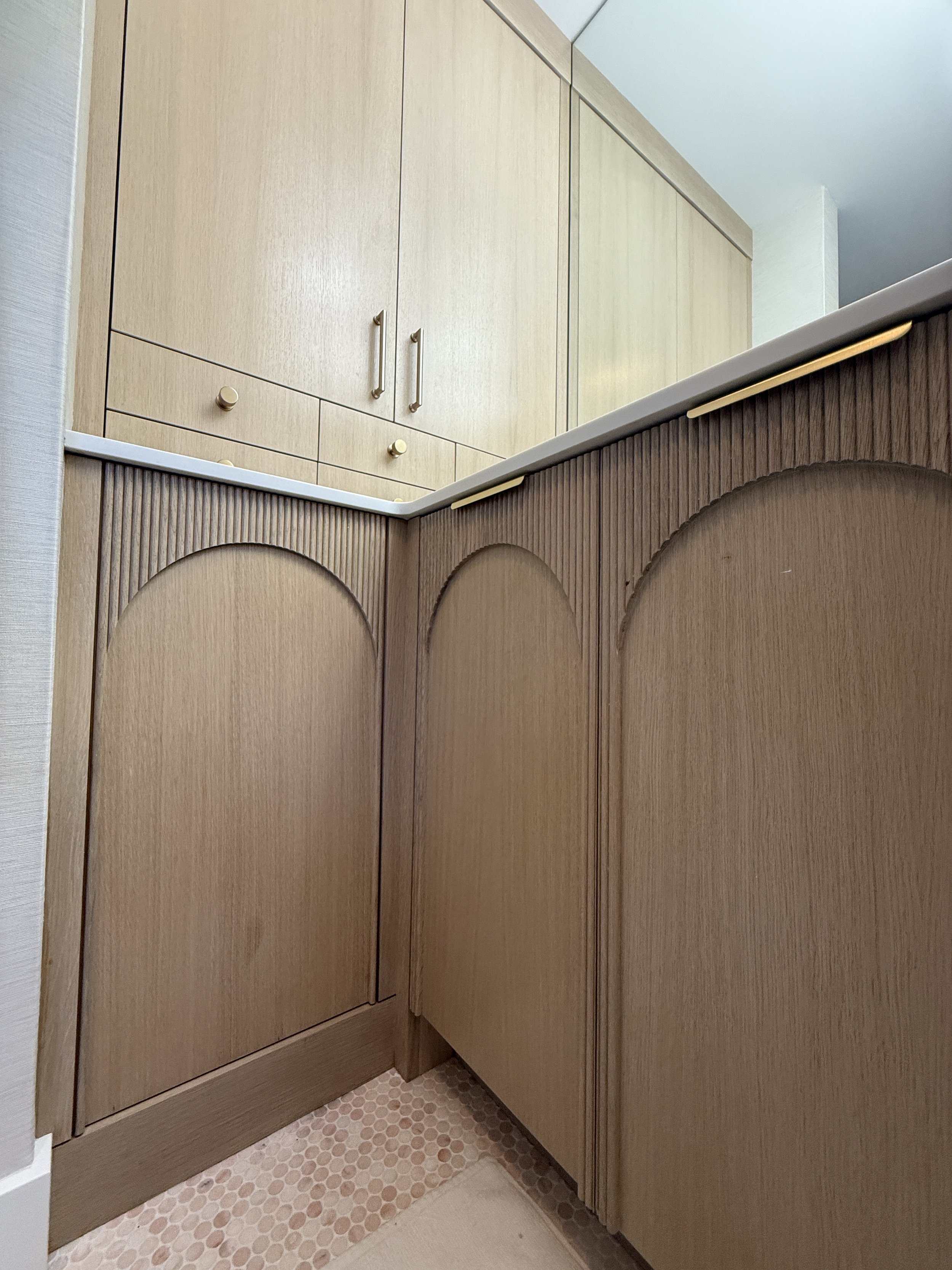 Close-up of beige wooden cabinets in a kitchen with circular patterned tile flooring.