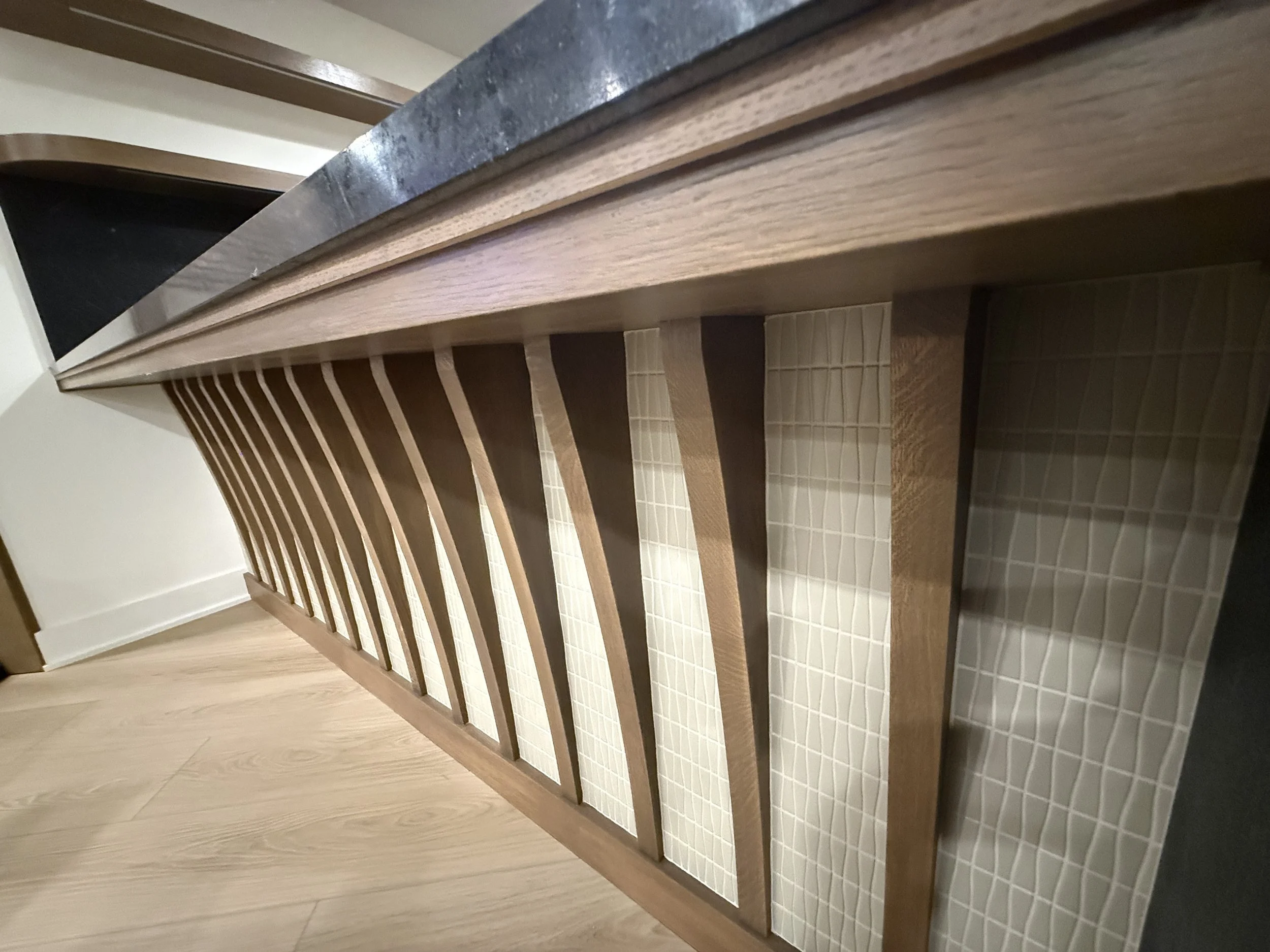 A wooden bed frame with evenly spaced slats and a decorative headboard, placed on a tiled floor in a room.