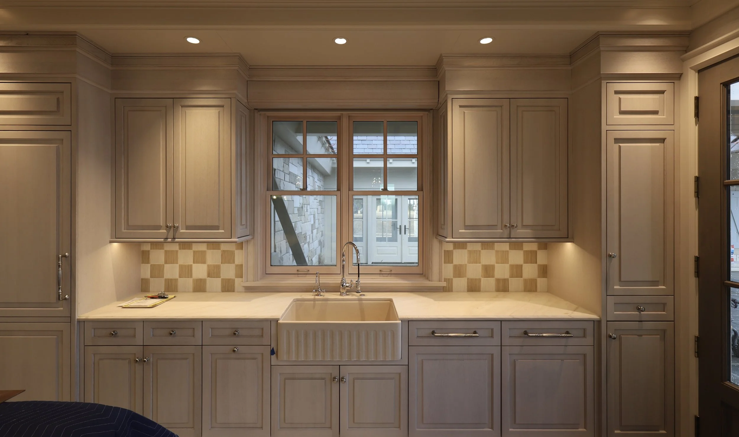 Kitchen with beige cabinetry, a window above the sink, and beige checkered backsplash tiles.