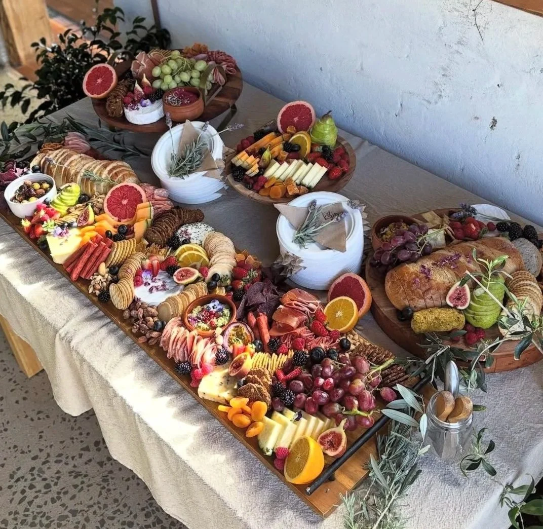 A table laden with an abundant assortment of cheeses, fruits, crackers, and charcuterie, arranged for a celebration or gathering.