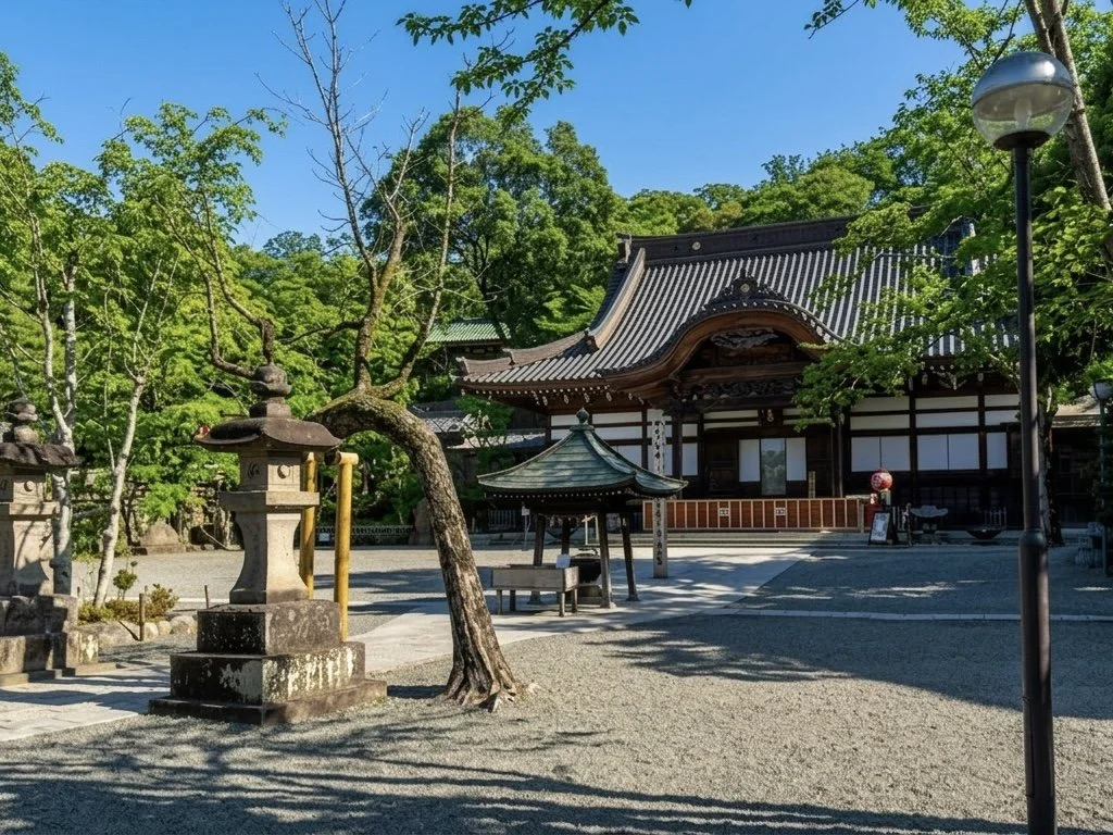 緑豊かな木々に囲まれた伝統的な日本の神社の境内。石の灯籠、祠、建物が見える。