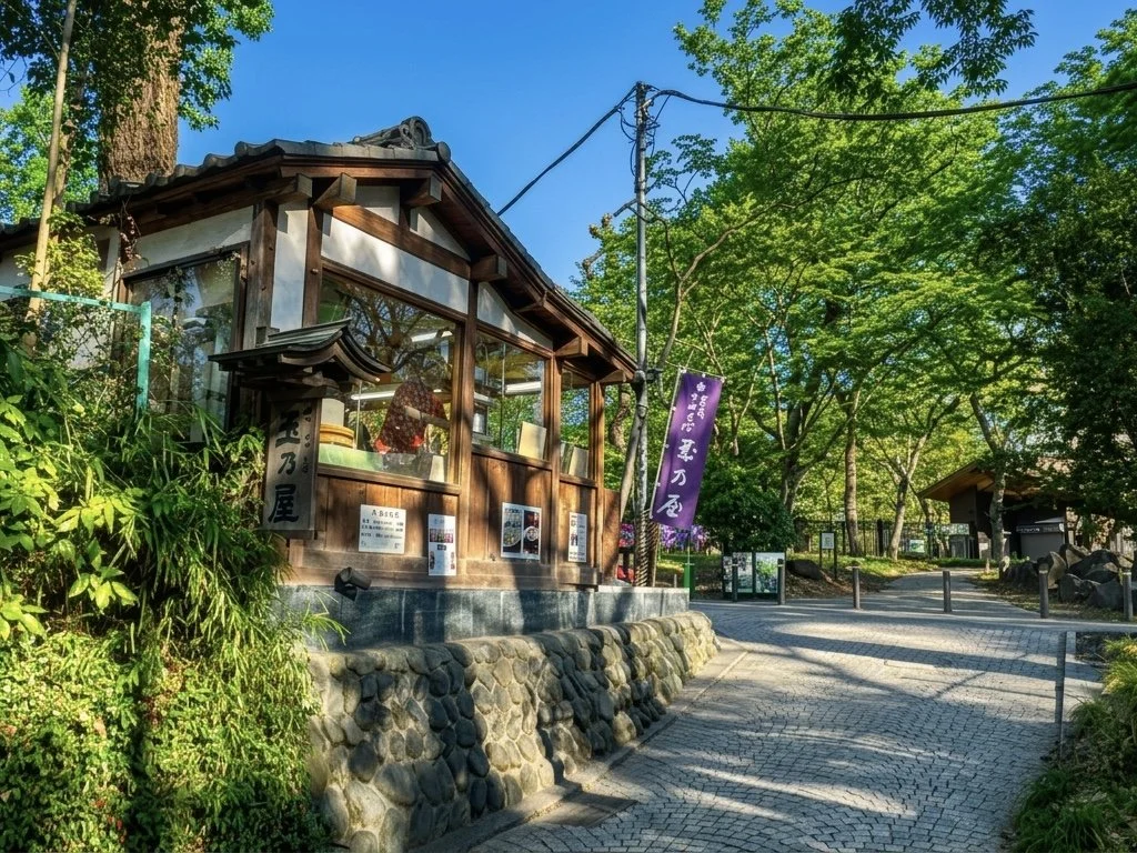 木々の茂る公園内の小さな木造の建物と石畳の道。