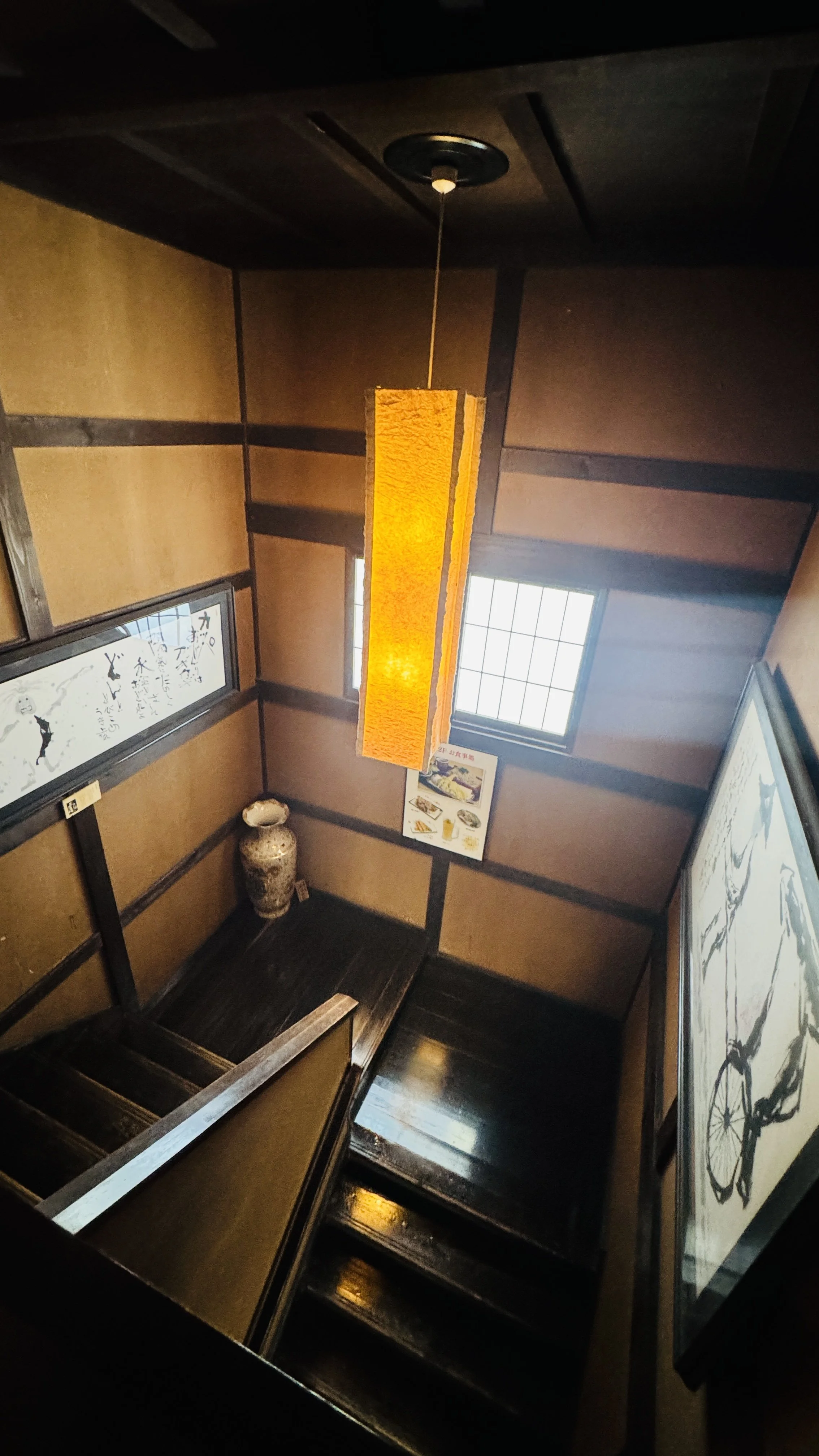木製の階段と壁に掛けられた絵画やスクリーン、天井には橙色の紙製のペンダントライトが吊るされている、和風の部屋の内部の風景です。」}#/json-schema-from-ImageAltText اسلامية: لا أستطيع رؤية الصور أو التعرف على محتوياتها، لذا لا أستطيع تقديم وصف دقيق لها. يرجى وصف الصورة لي بشكل أكثر تحديدًا أو إرسال صورة نصية.}}#/json