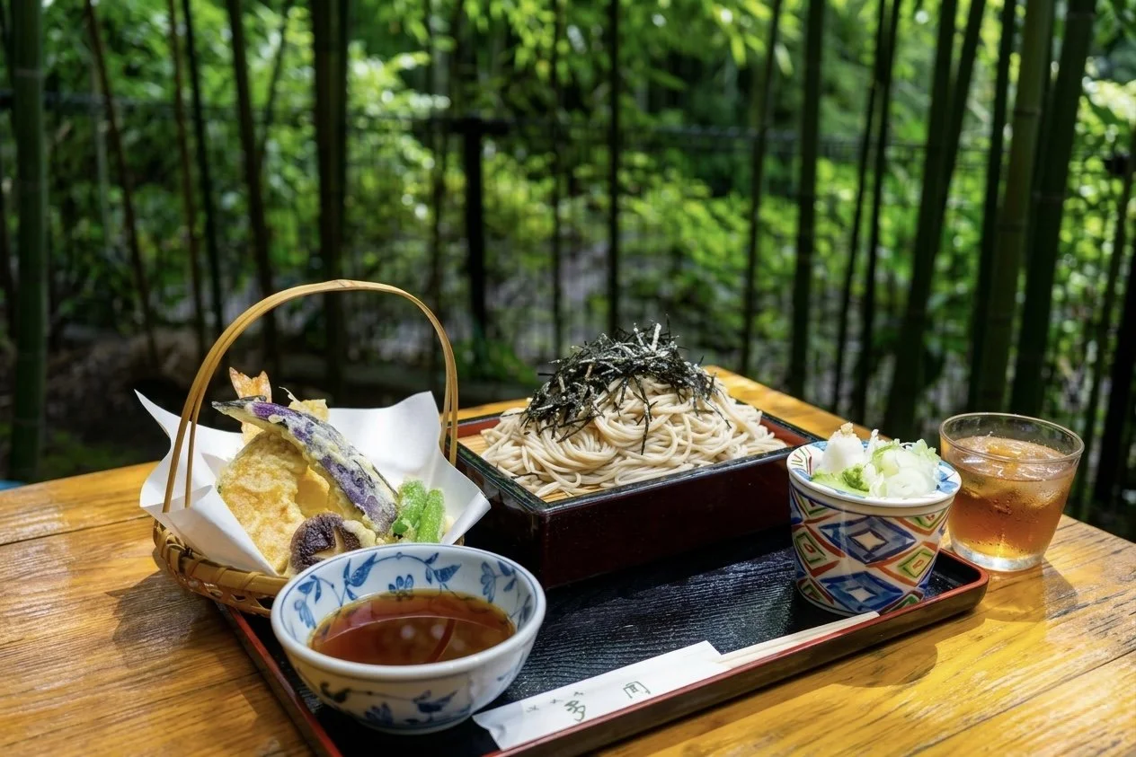 竹の庭のテーブルに盛り付けられた日本のそば料理と天ぷらのセット