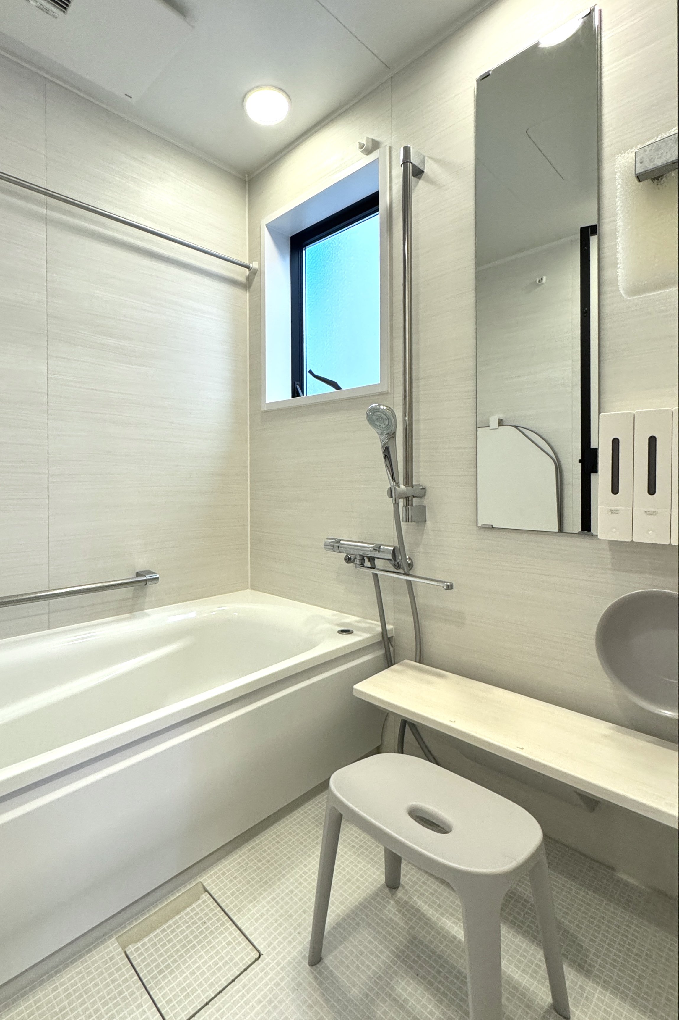 清潔なシャワールーム、バスタブ、ミラー、トイレと洗面台、収納棚、窓と手すりがある浴室の interior.