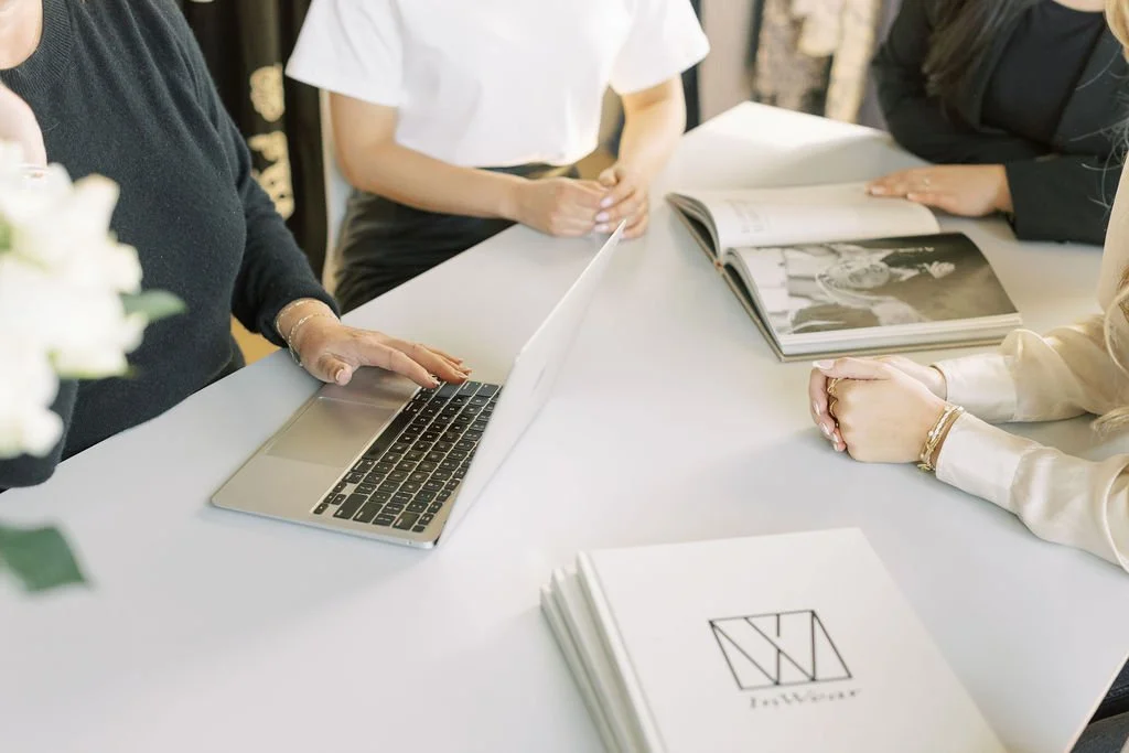 Susan Cooper Agency team sitting around a white table, looking at a laptop and a photo book, with an Inwear brand book on the table.