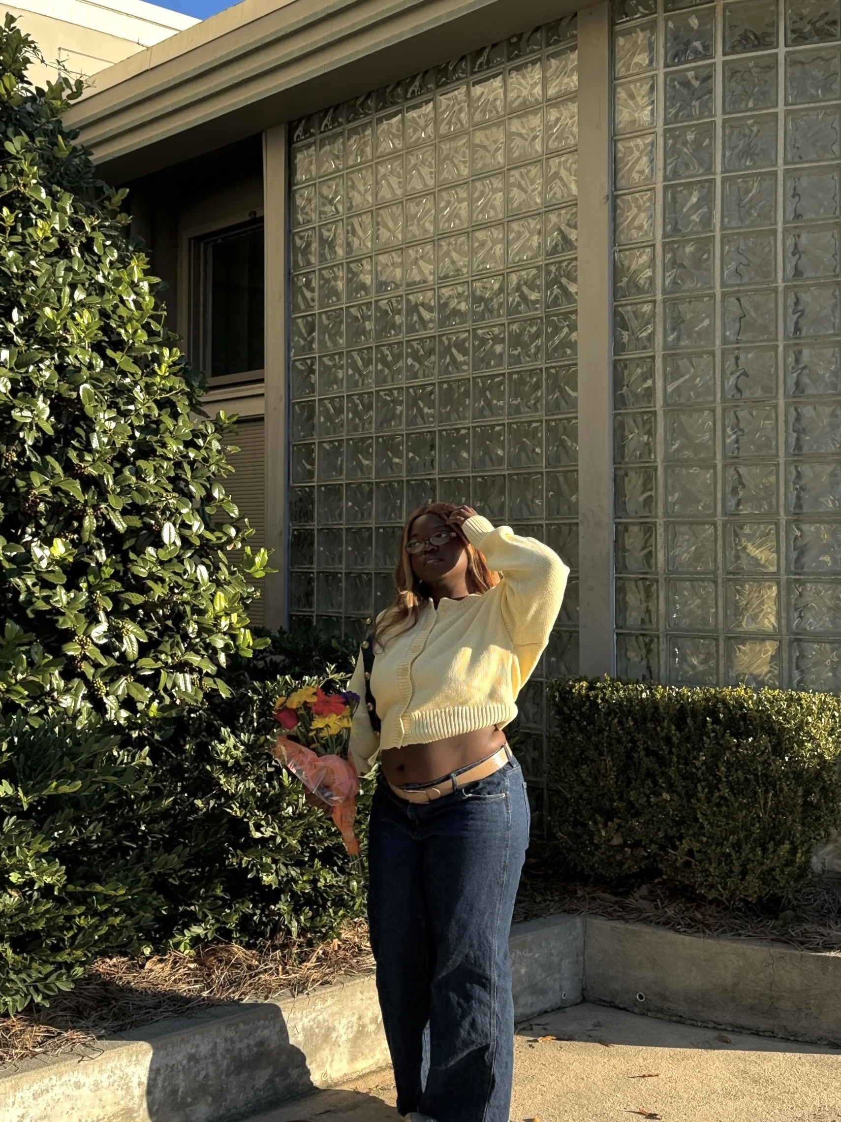 Lifestyle outfit shot of a woman in blue jeans and a yellow sweater representing Susan Cooper Agency