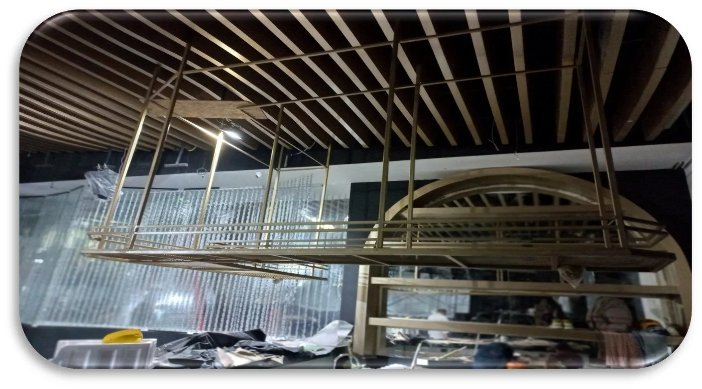 Una estructura de hierro pintada de dorado en proceso de fabricación o montaje, ubicada en un taller. En el fondo hay un arco de madera y herramientas dispersas.
