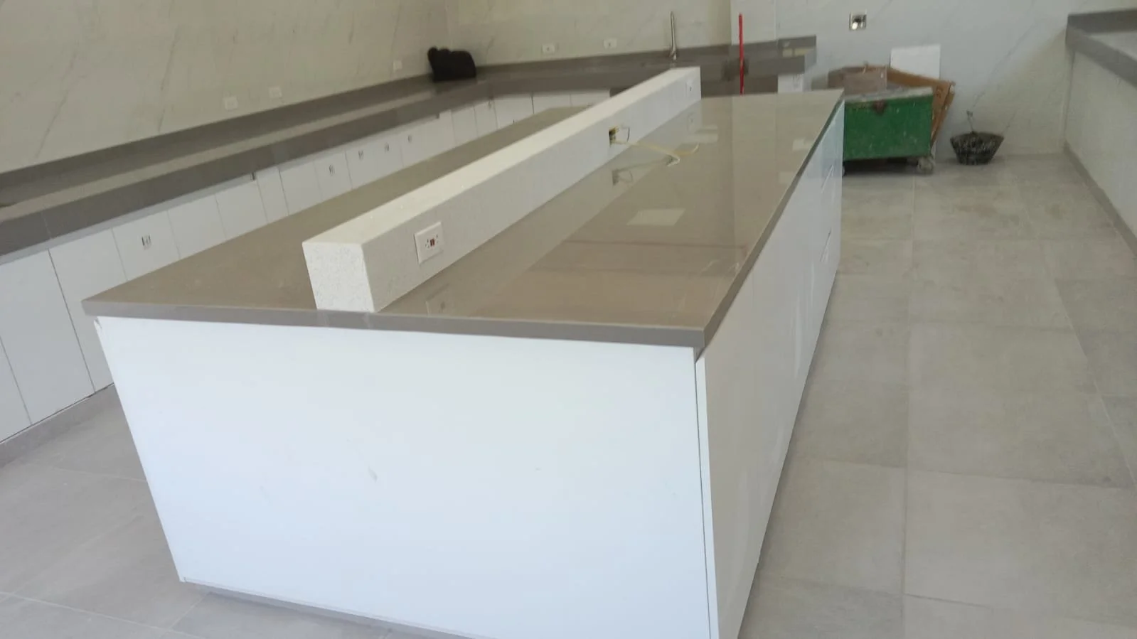 Mostrador de cocina en construcción con tomas eléctricas y balde de basura en el fondo.