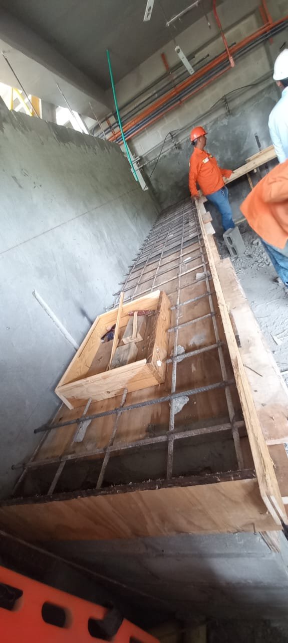 Trabajadores en un sitio de construcción colocando estructura de hierro y encofrado de madera para una losa.