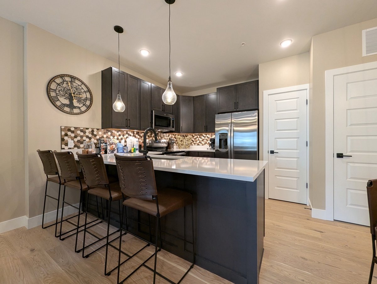 Modern kitchen room inside Crystal Cottage at Brightwood, featuring dark wood, cream walls, modern, stainless steel appliances, and pendant lighting.
