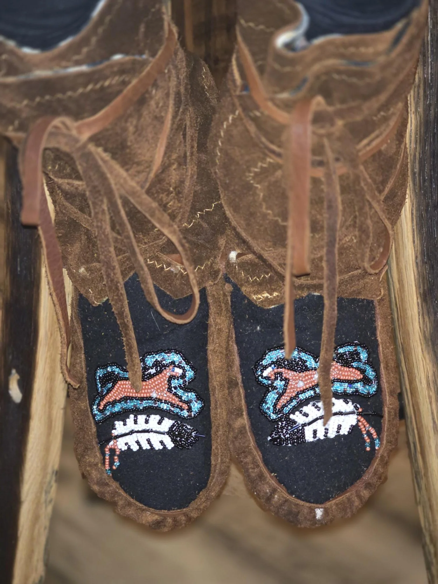 Buffalo hide wrap around moccasins with beaded horse and feathers.